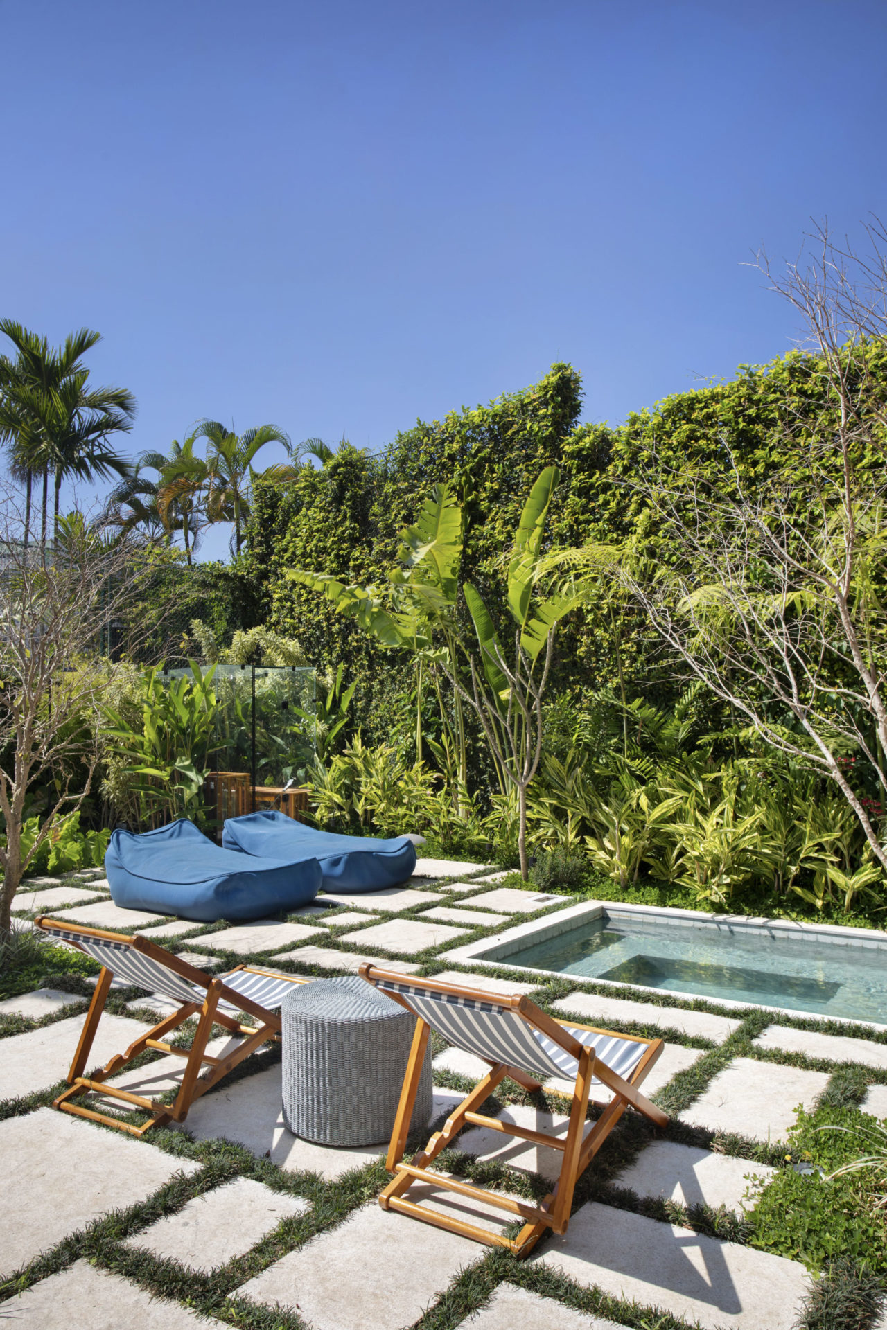 na foto piscina, com espreguiçadeiras e muito verde ao redor