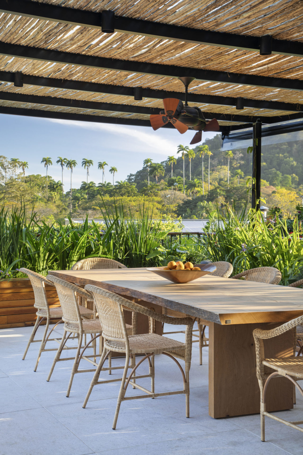 na foto pergolado, mesa de jantar e muito verde ao redor