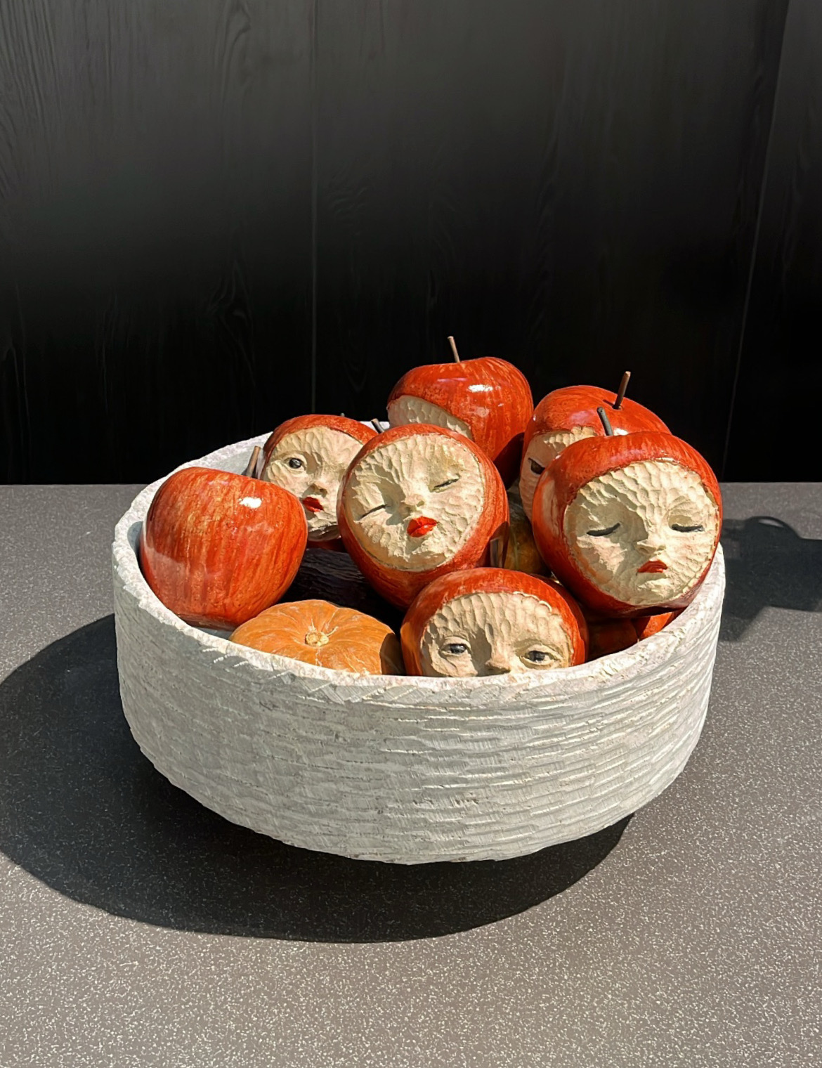 na foto uma obra de arte que são pequenas maçãs com rostos esculpidos