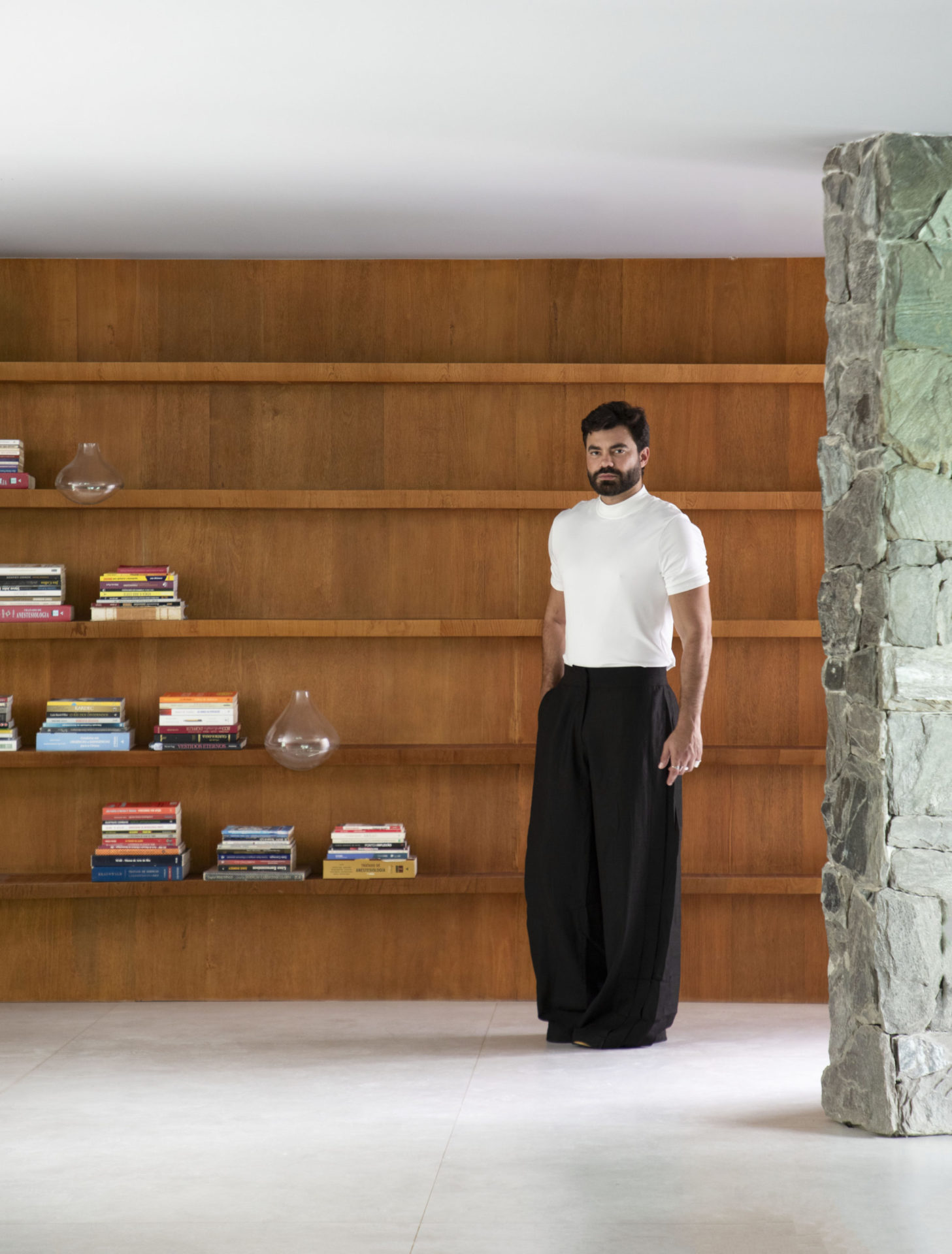 na foto parede com estante em madeira e homem branco em pé