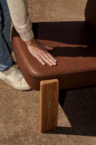 na foto uma cadeira de couro e a mão de um homem no assento