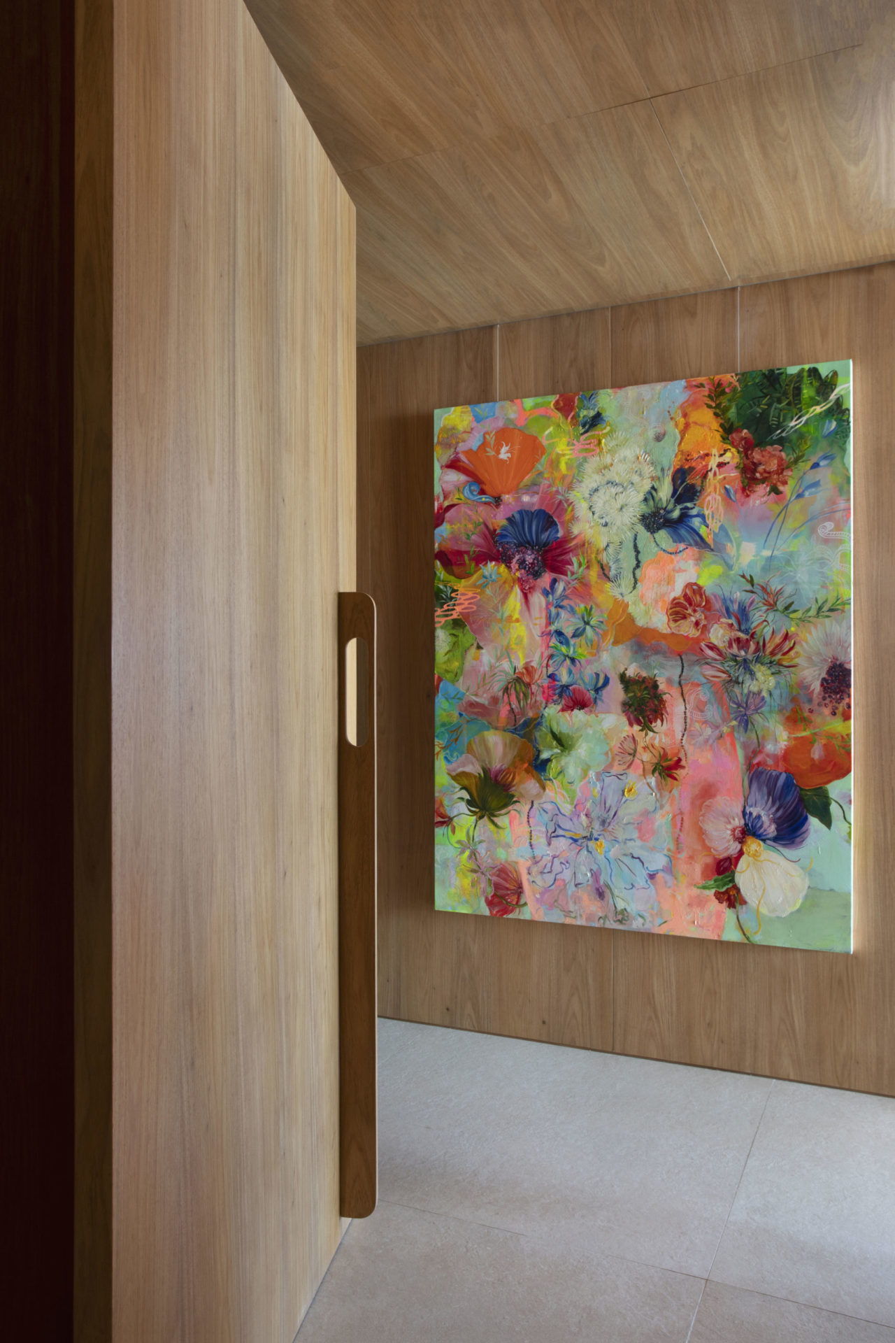 na foto uma porta de madeira aberta, uma parede de madeira com grande quadro colorido