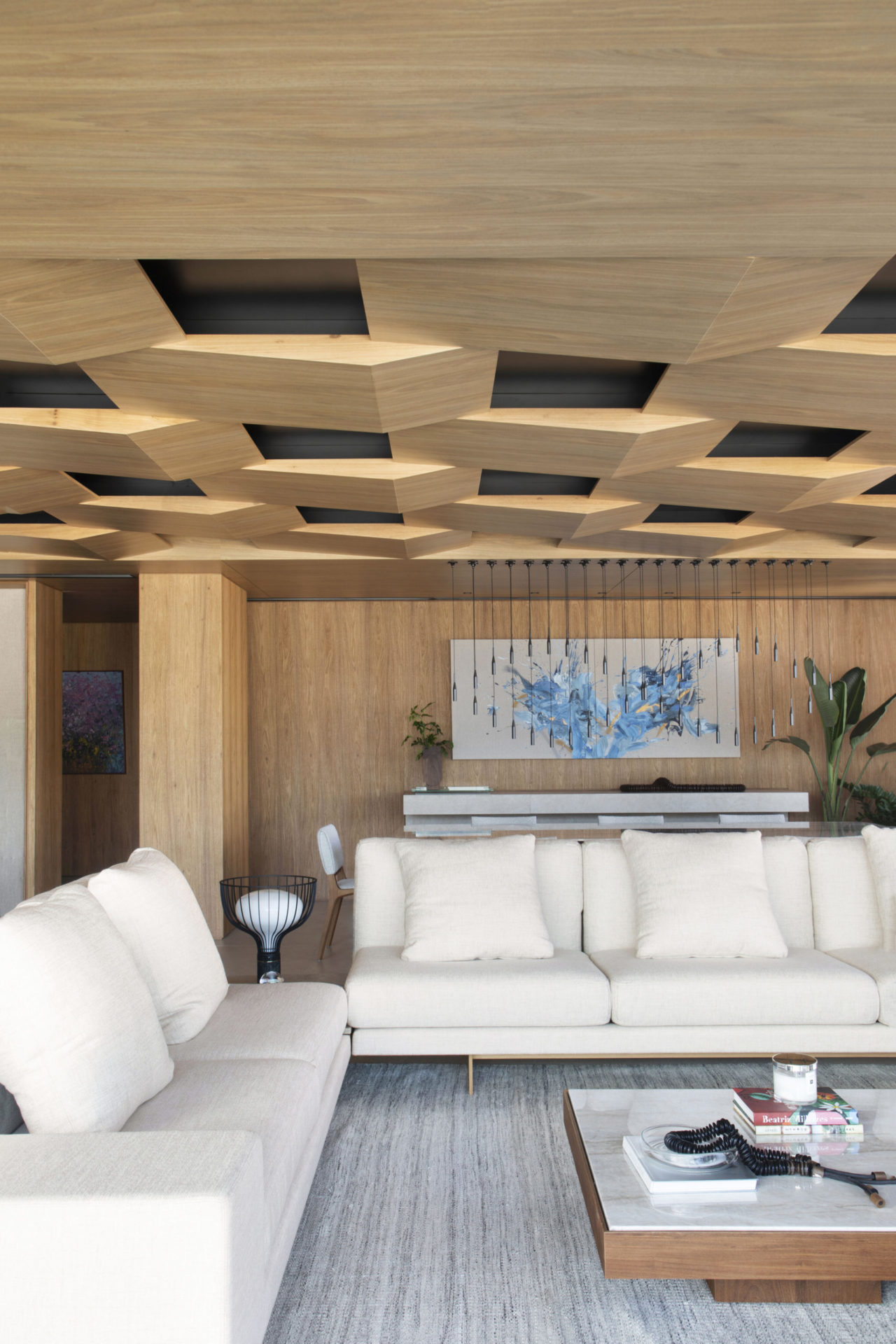 na foto sala com dois sofás brancos e teto forro de madeira com padrões geométricos