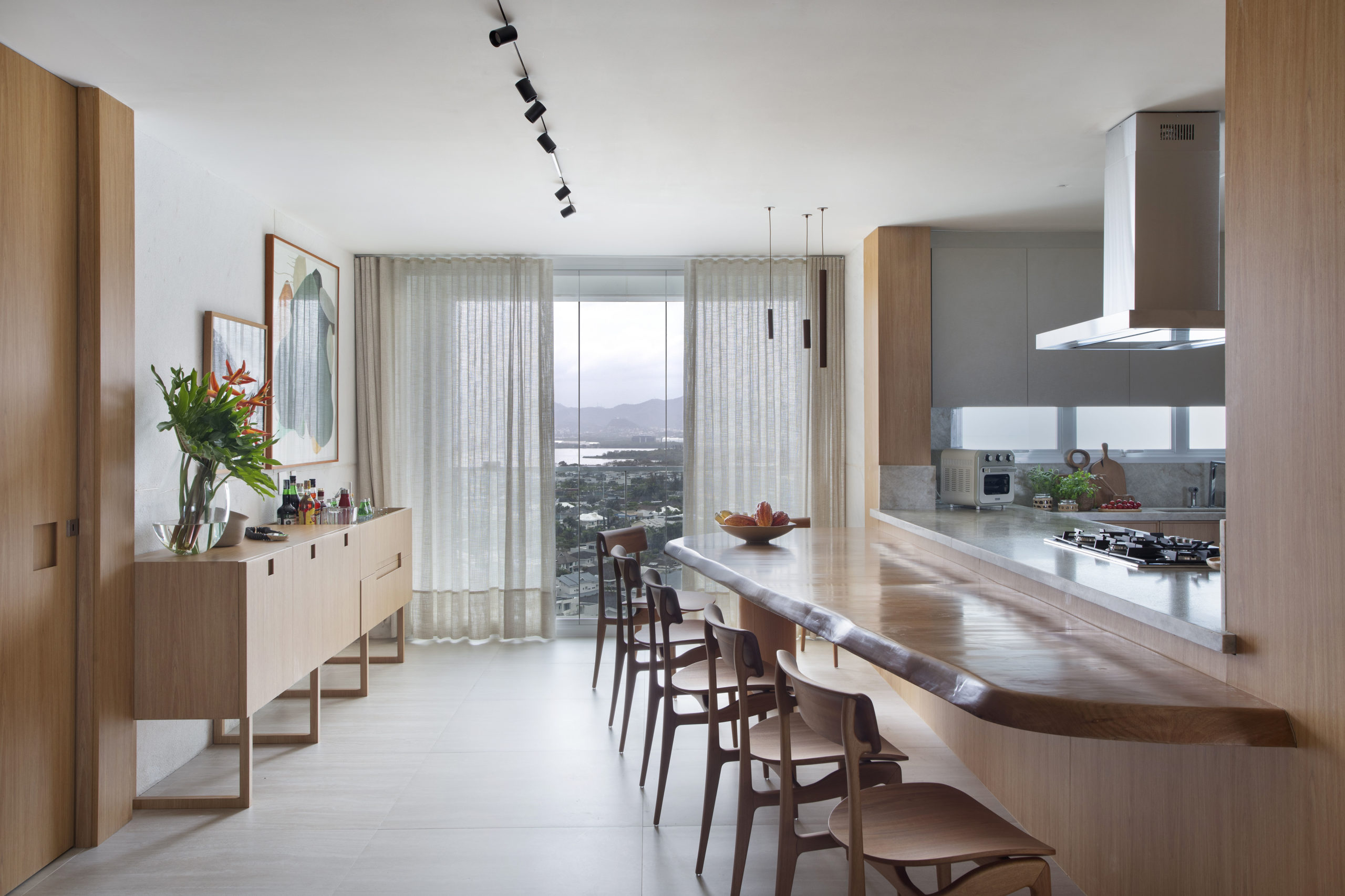 na foto bancada de cozinha com banquetas e grande janela