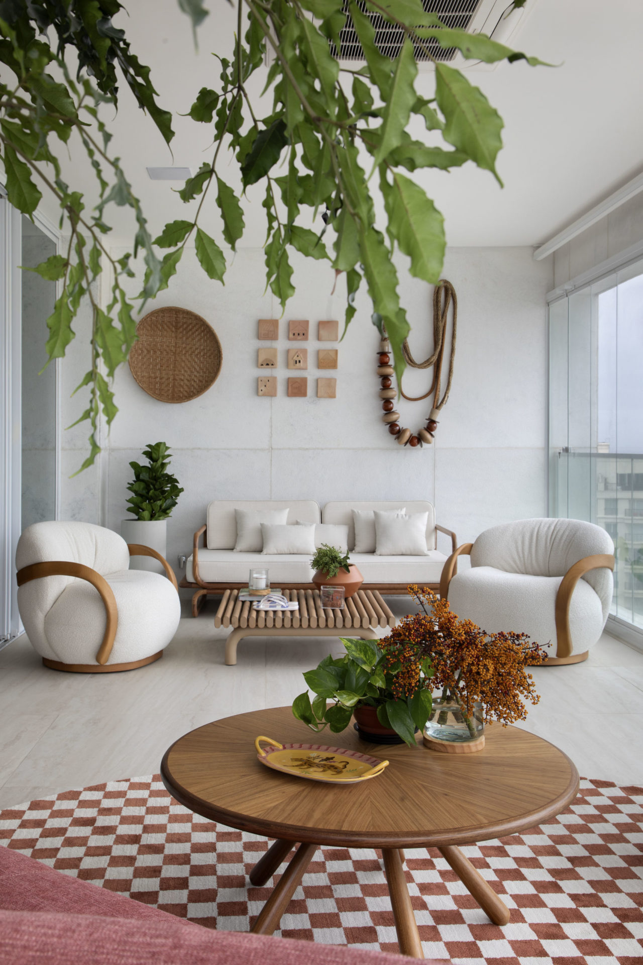 na foto cômodo de apartamento com sofá branco, poltronas brancas e tapete quadriculado em branco e vermelho