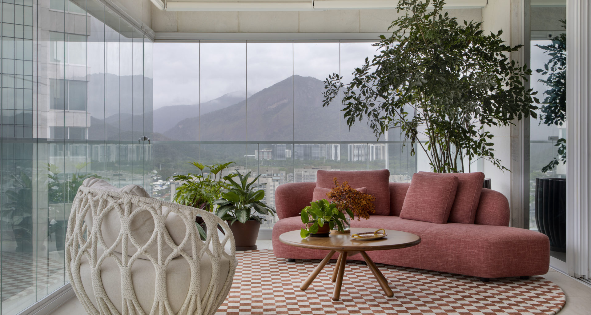 na foto varanda com poltrona, mesa de centro, tapete quadriculado e sofá na cor terracota