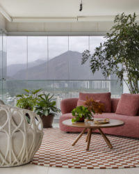 na foto varanda com poltrona, mesa de centro, tapete quadriculado e sofá na cor terracota