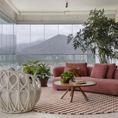 na foto varanda com poltrona, mesa de centro, tapete quadriculado e sofá na cor terracota