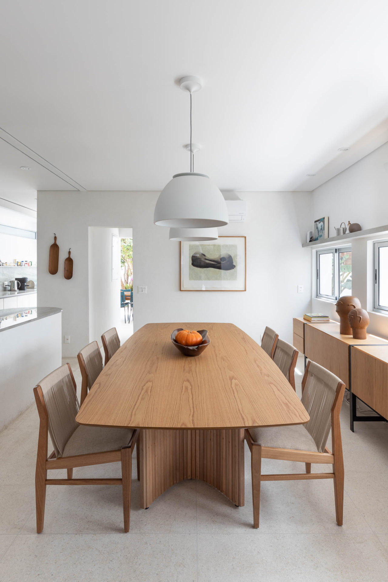 na foto mesa de jantar de madeira clara e janelas