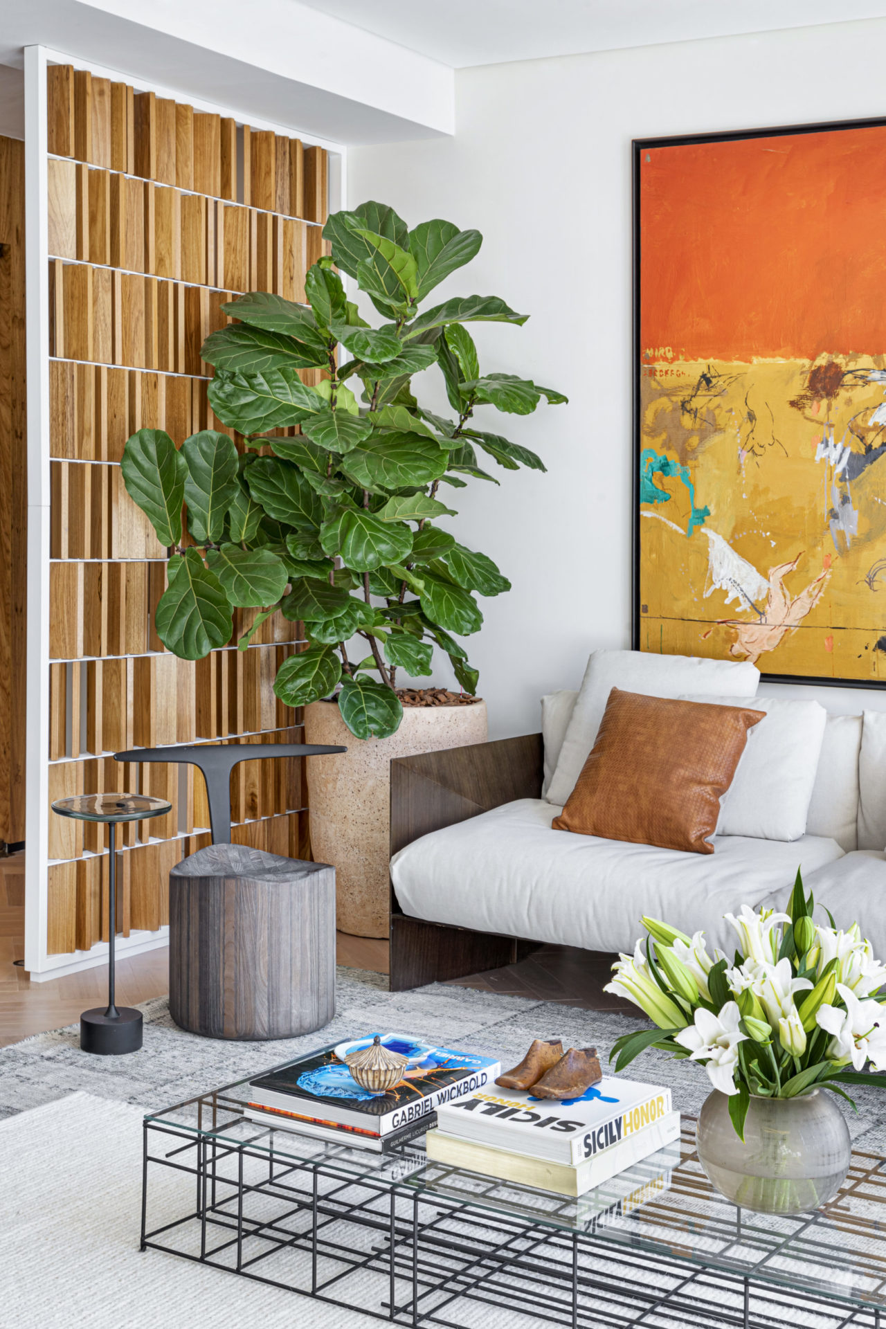 na foto sala com sofá branco, vaso de planta e quadro colorido nas cores amarelo e laranja