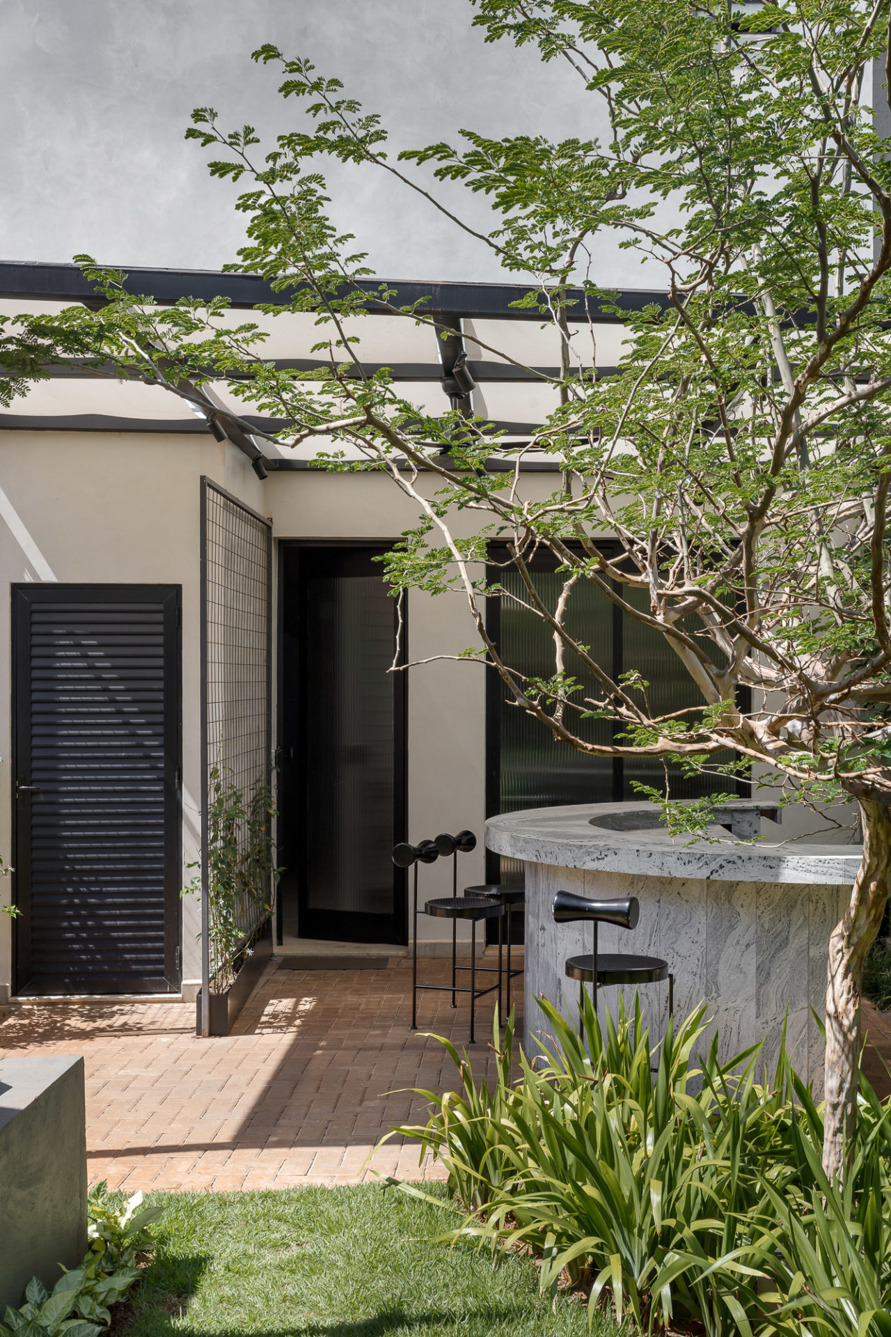 na foto área externa de clinica com banquetas e muito verde