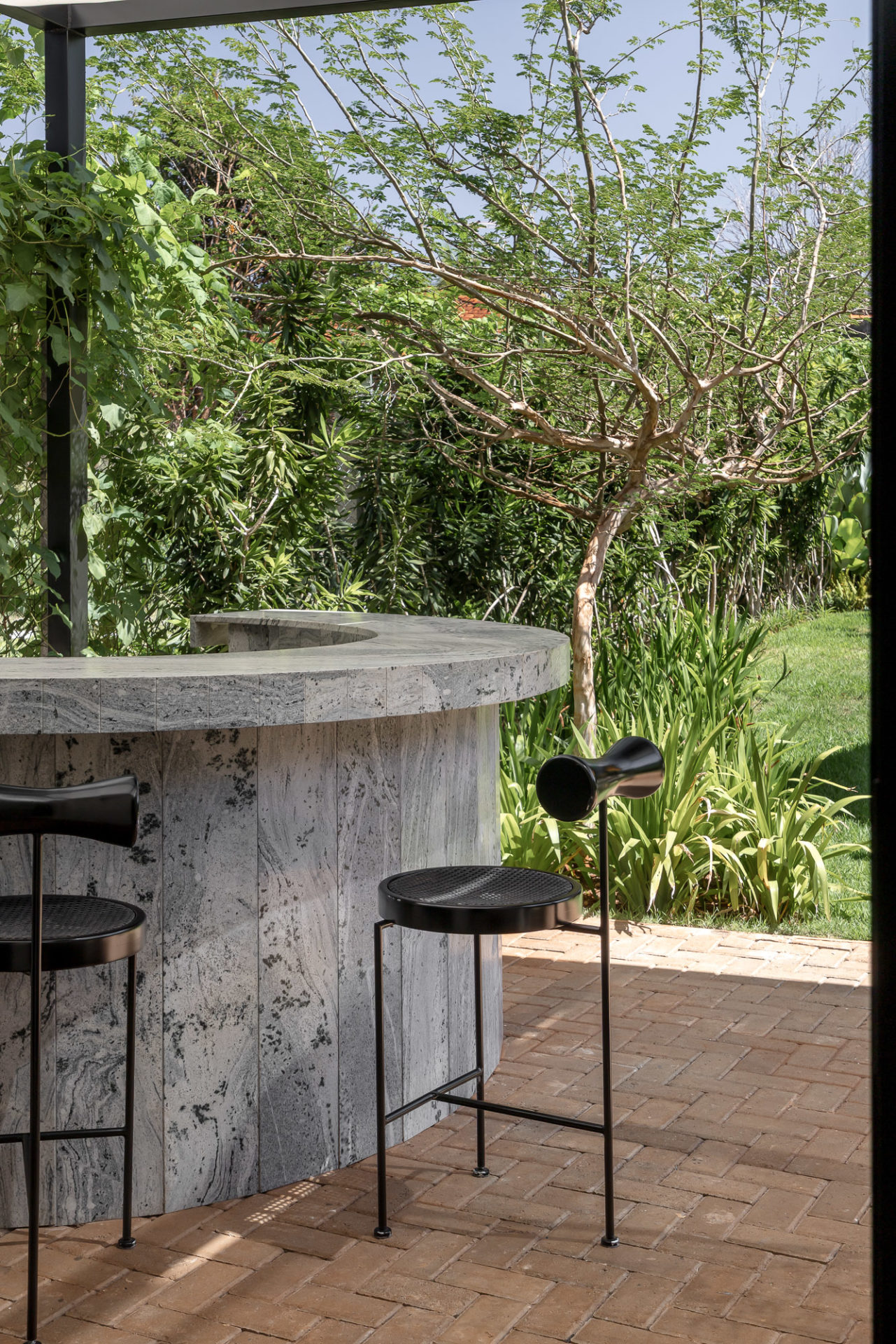 na foto área externa com banquetas pretas e muitas árvores