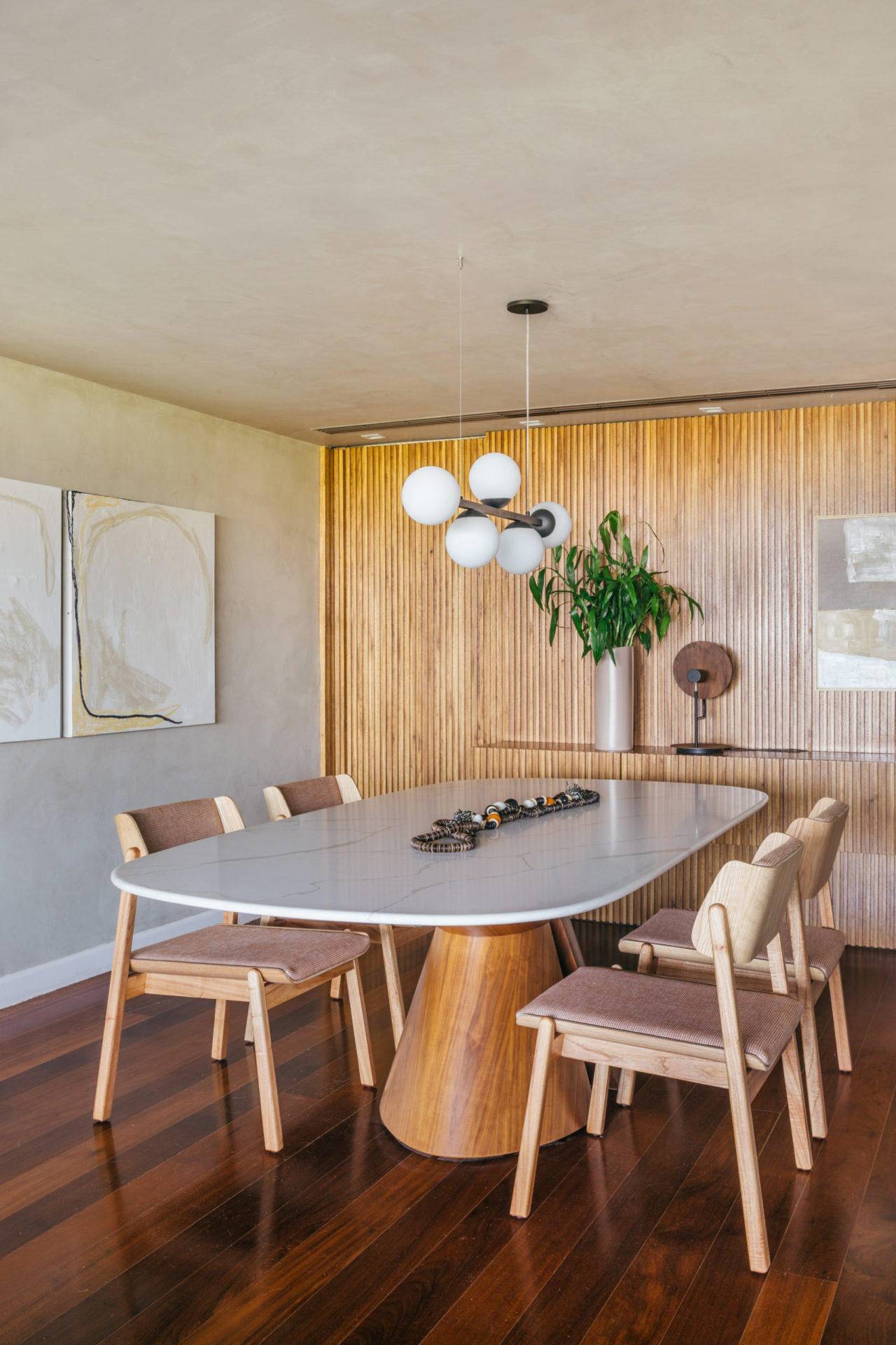 na foto sala de jantar com mesa para quatro pessoas, parede de madeira ripada