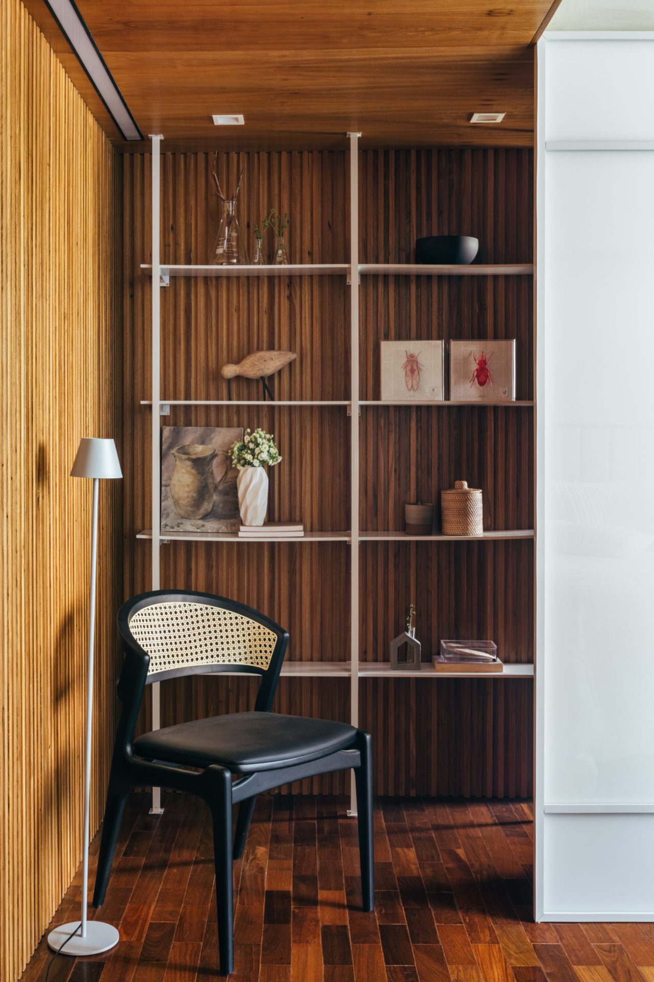 na foto cômodo de apartamento com estante na parede e cadeira preta