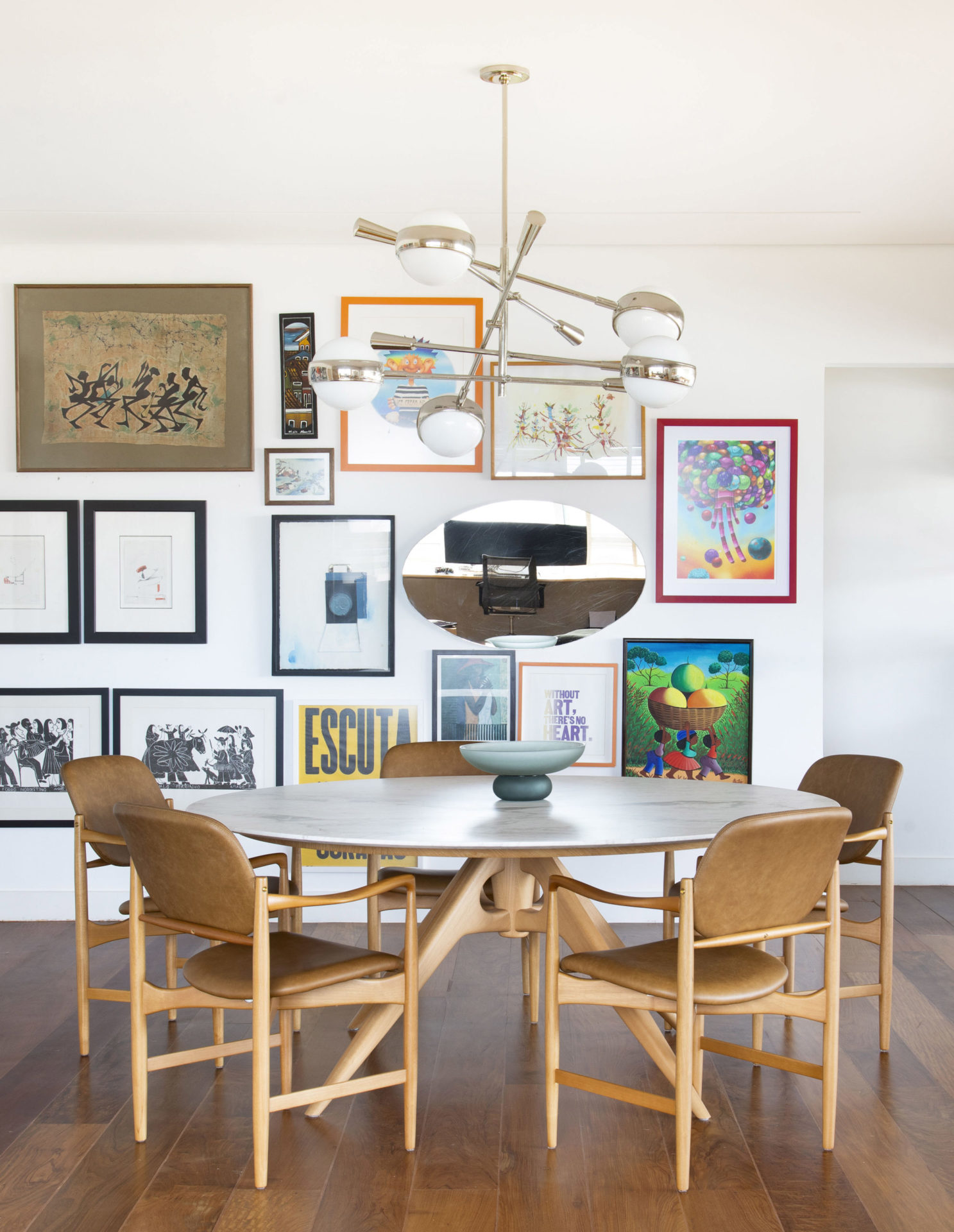 na foto sala de jantar com mesa de jantar e quadros na parede branca