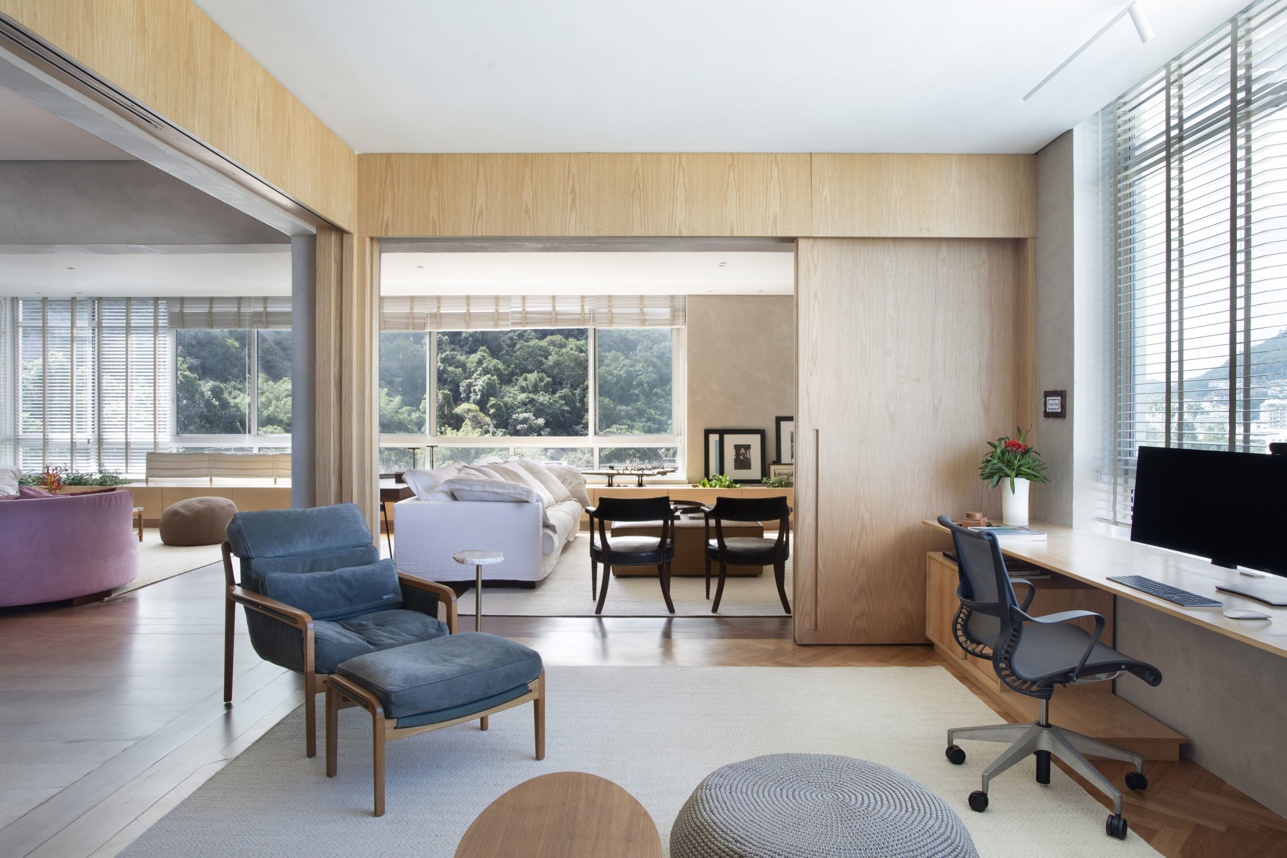 na foto poltrona com banqueta Pitu, de Aristeu Pires, estofada em lona verde e posicionada no espaço de trabalho como ponto de cor