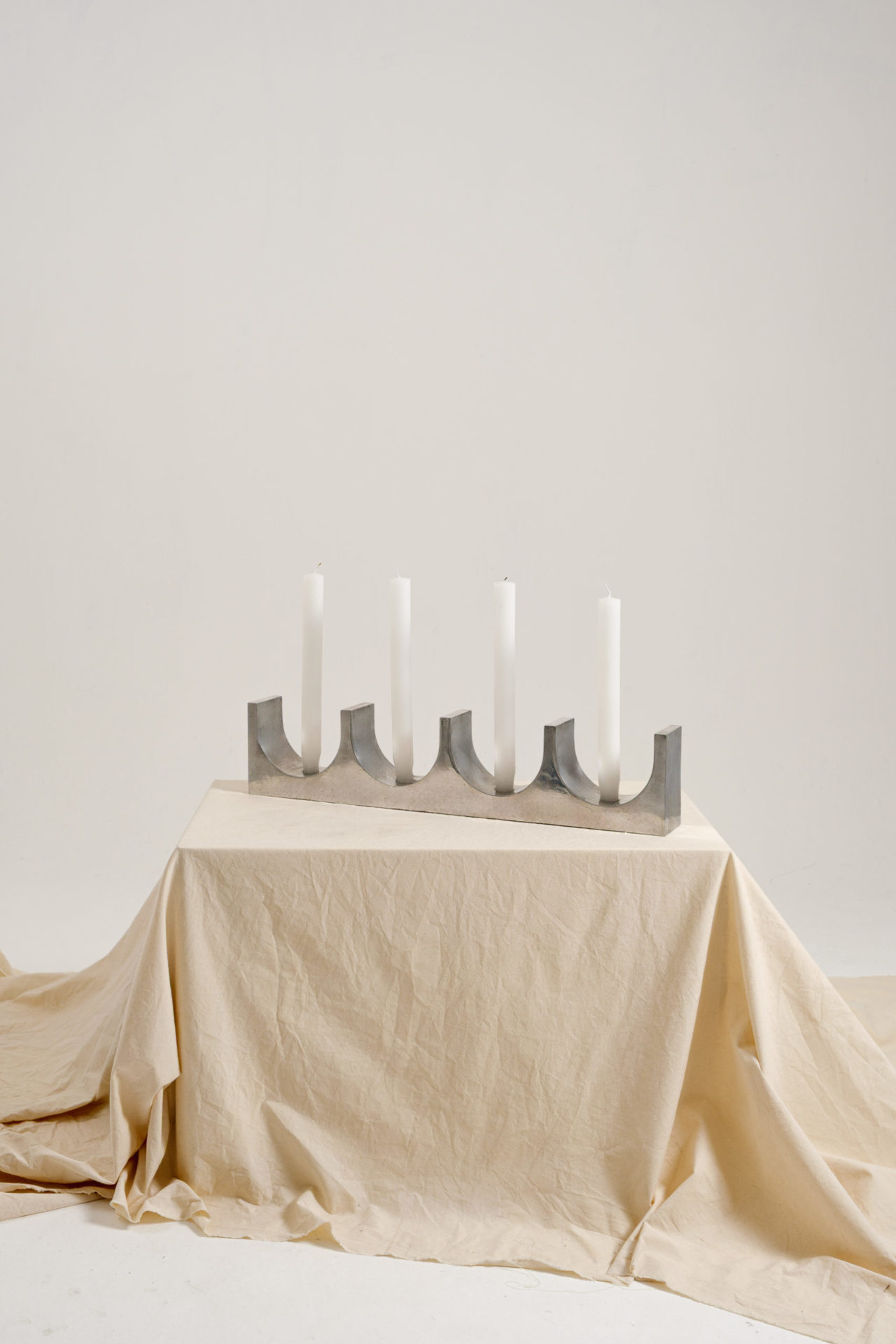 na foto candelabro em alumínio em uma mesa com toalha branca