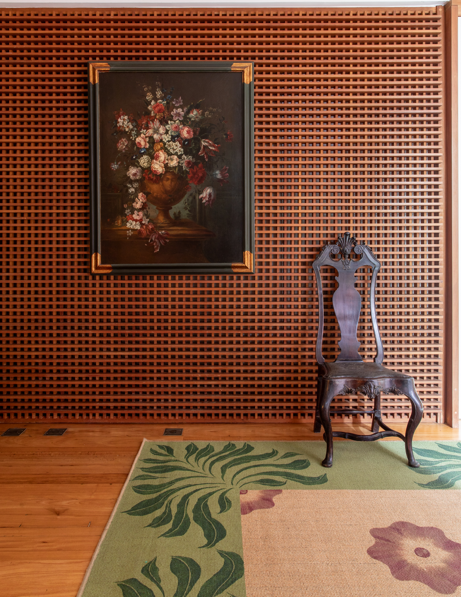 Hallde entrada de uma casa, com detalhe de parede em muxarabi e uma quadro de flores.