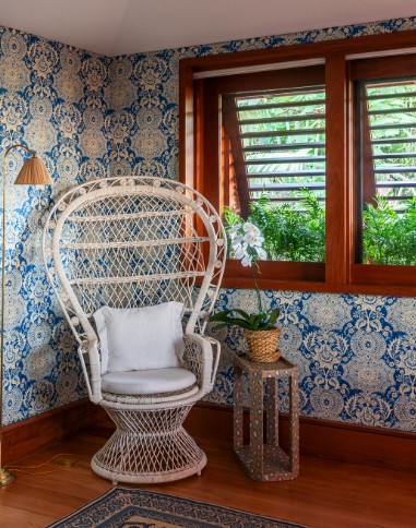 Paredes com tecido estampadao de azul , janelas em treliça controlam a luminosidade, detalhe de uma cadeira peacook 