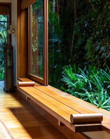 Janela com banco em madeira em toda e extensão, e ao fundo uma parede verde.