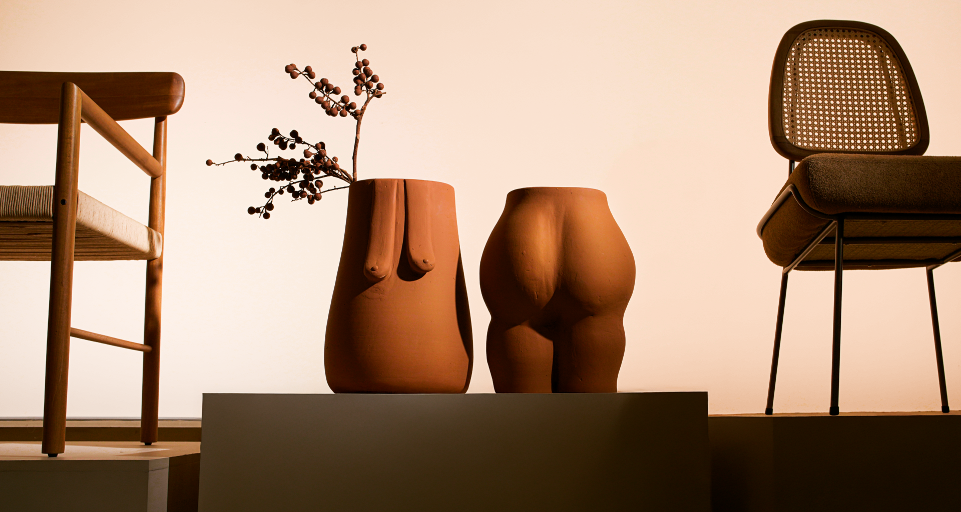na foto objetos de cerâmica em formatos do corpo feminino e duas cadeiras