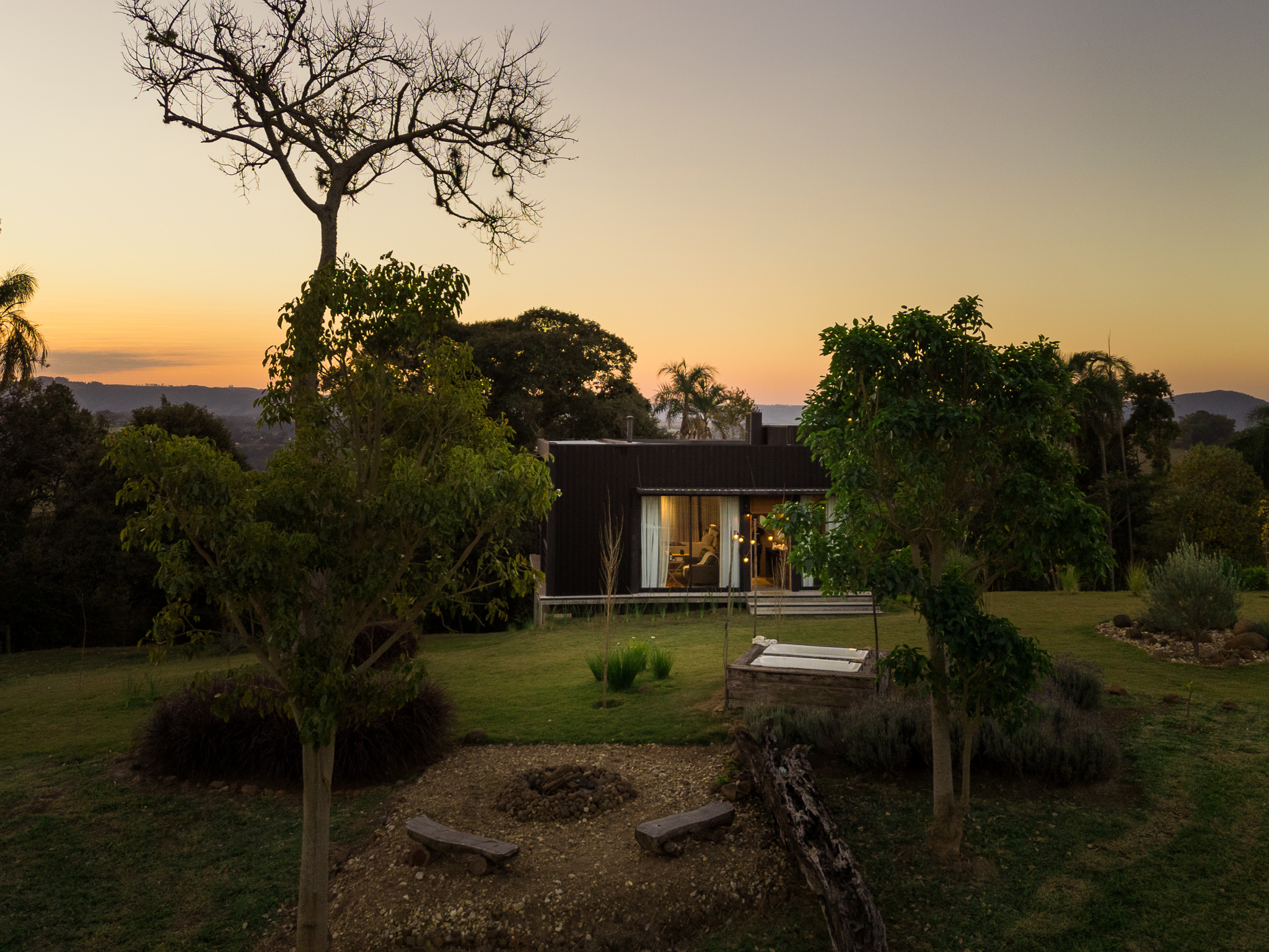 cabana metálica na cor preta e muito verde ao redor