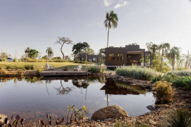 na foto área externa da cabana metálica com grande lago em seu entorno