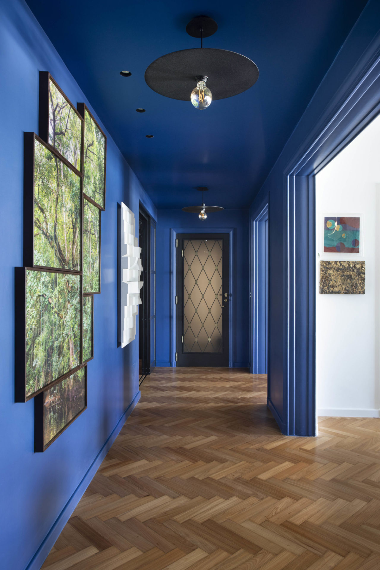 na foto corredor de apartamento na cor azul bic com quadros na parede