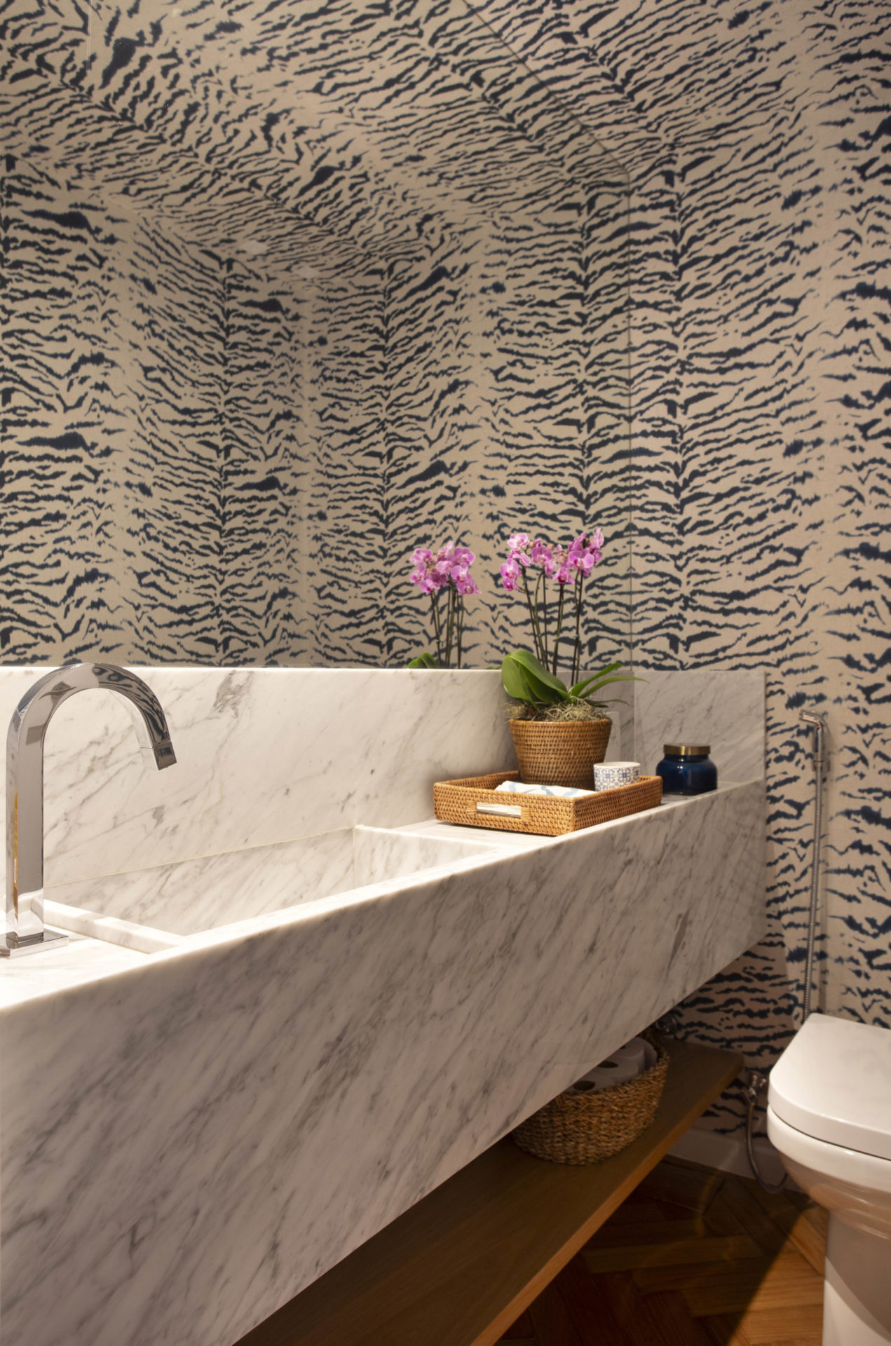 na foto lavabo com grande bancada e papel de parede 