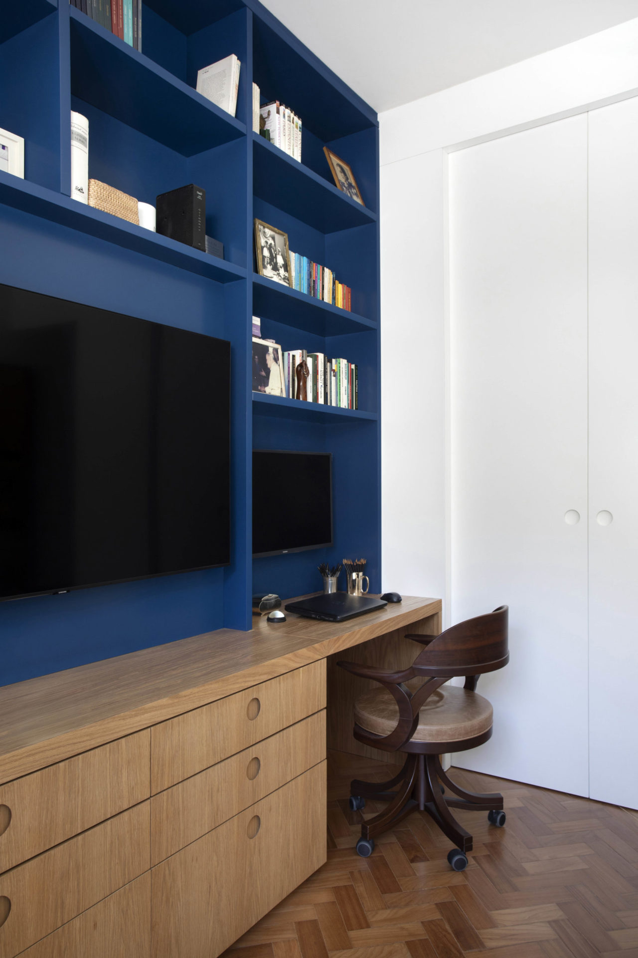 na foto escritório de apartamento com destaque para estante na cor azul-bic