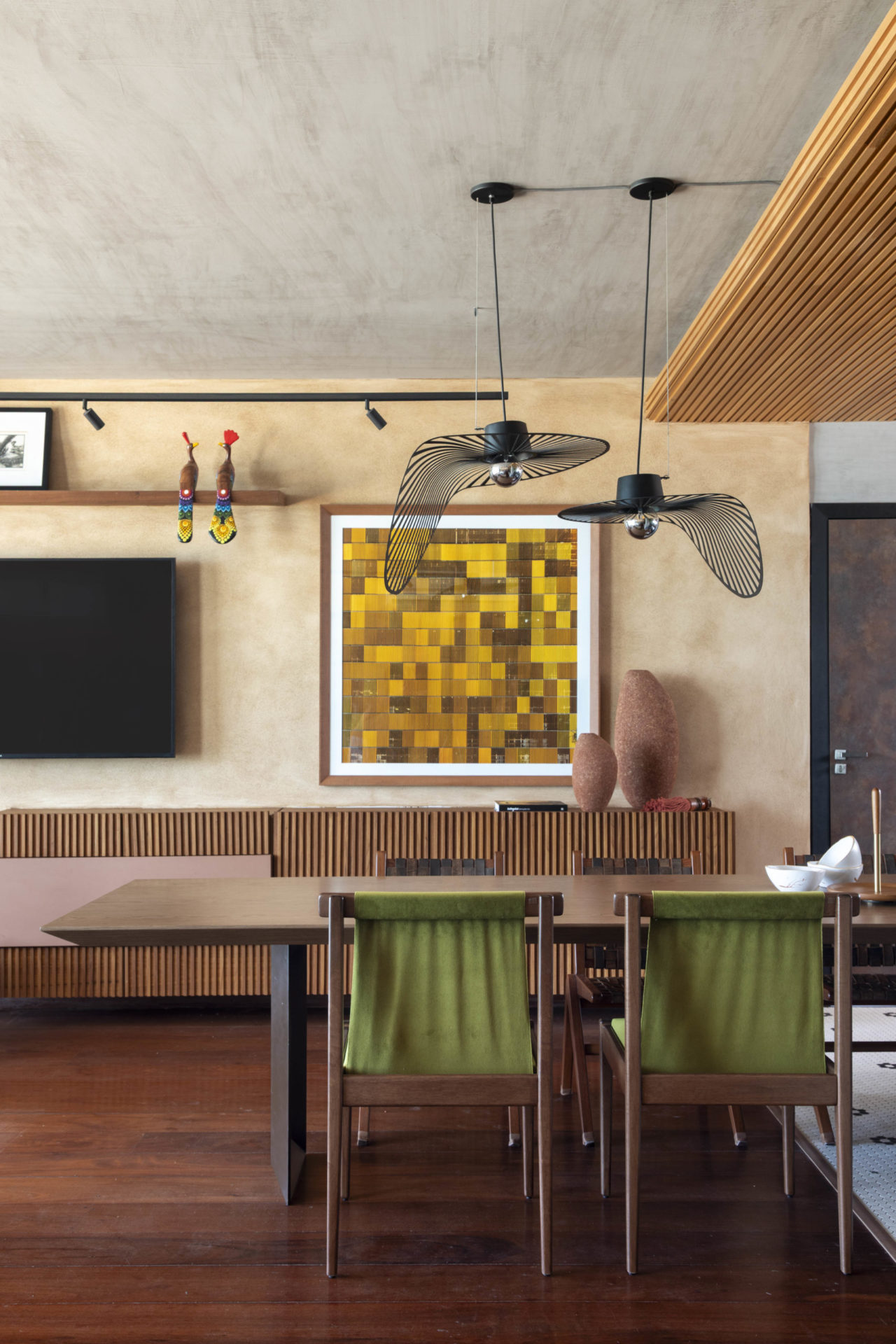 na foto sala com mesa de jantar, ventilador de teto e parede com tv e quadro