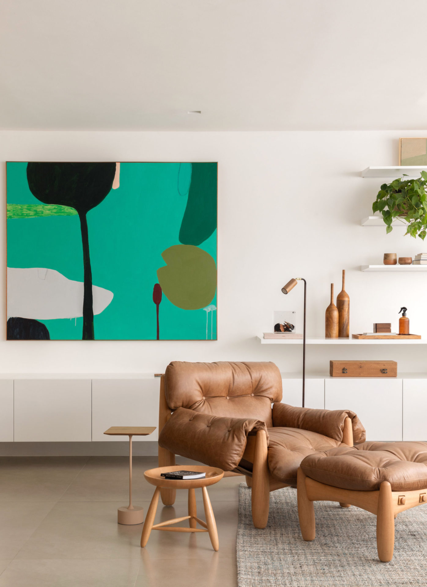 na foto sala com quadro verde na parede e uma poltrona mole de couro