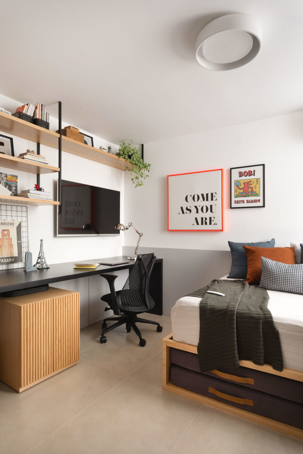 na foto quarto com cama, mesa de estudo e tv na parede