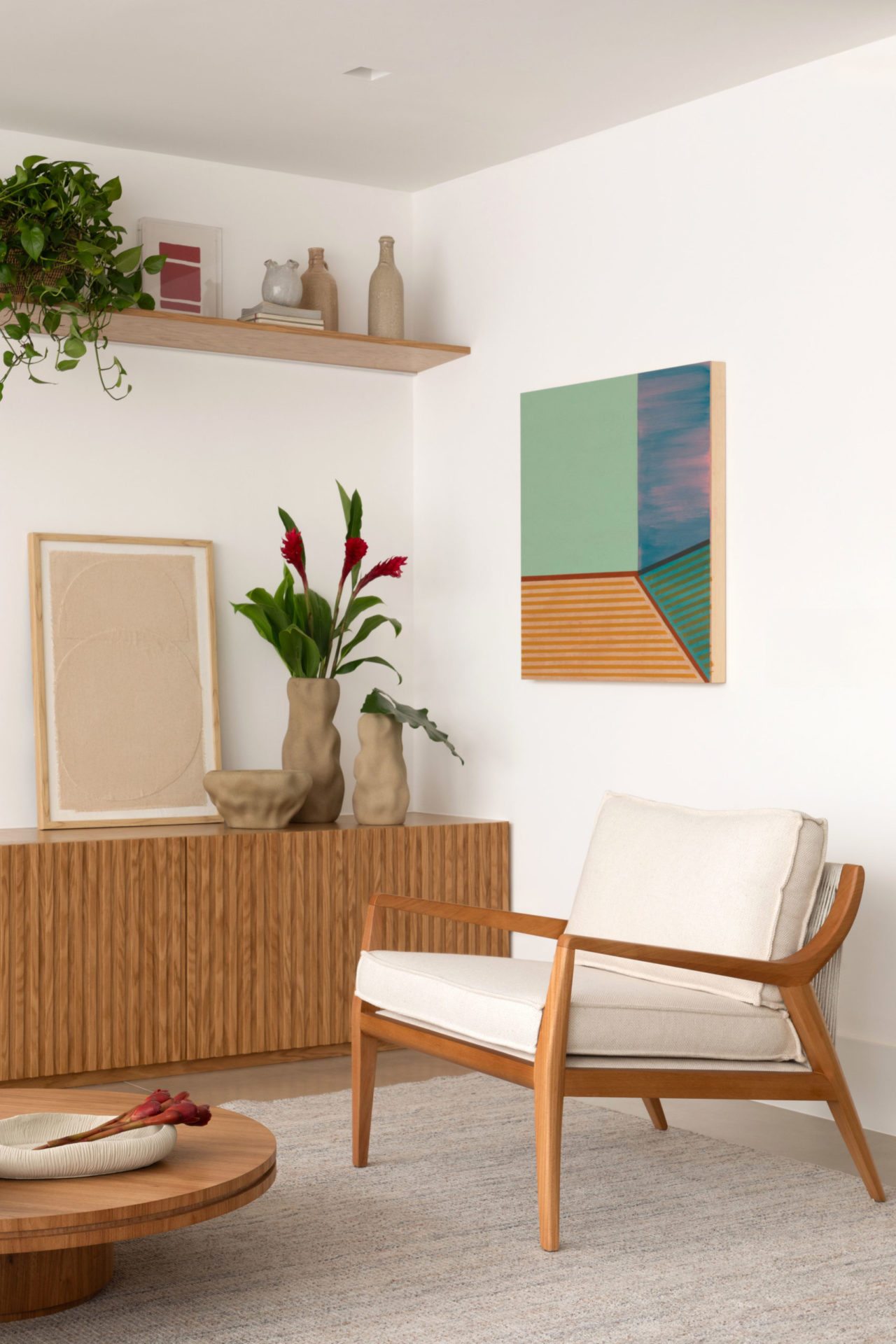 na foto sala com uma cadeira branca, quadro geométrico na parede