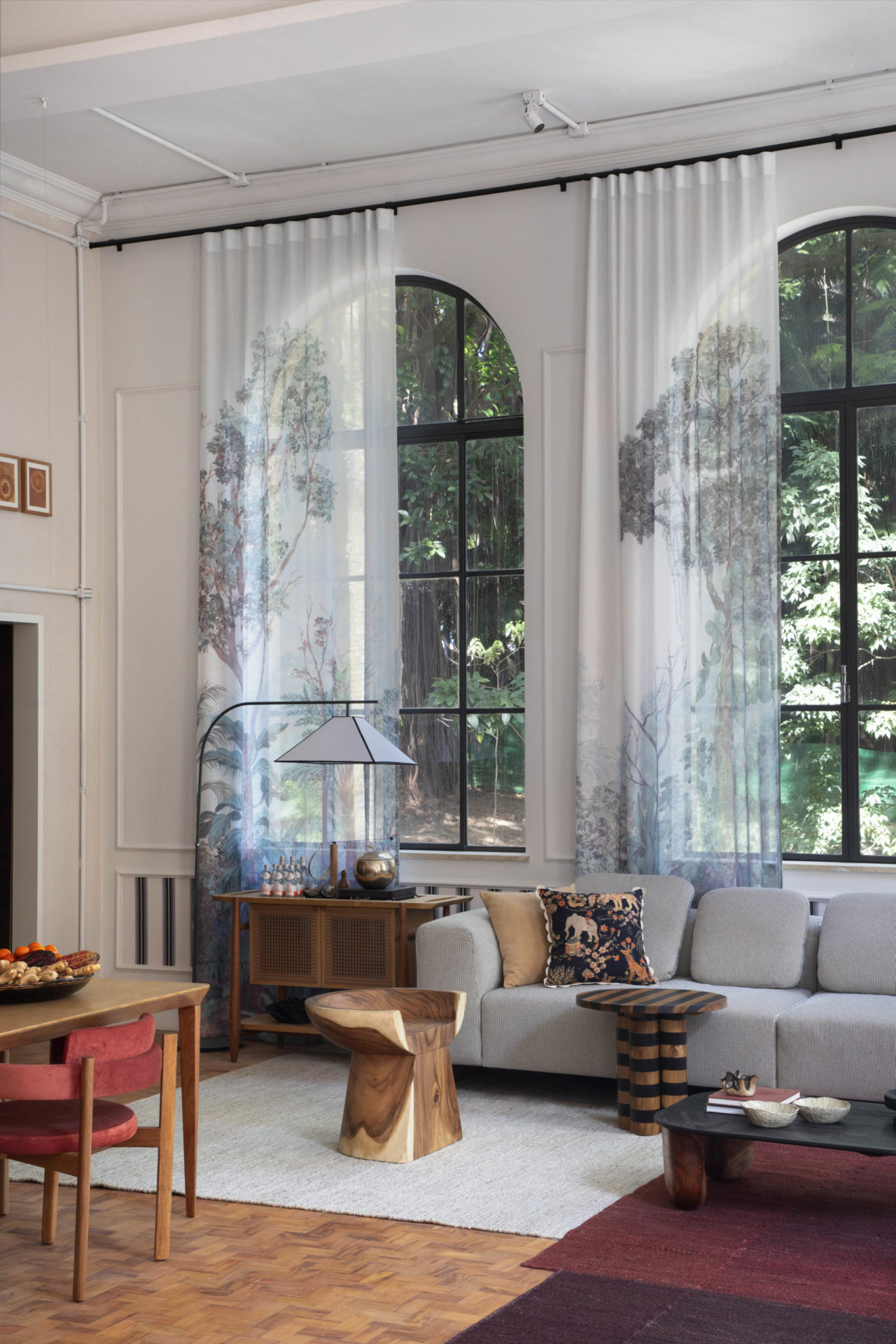 na foto loft com grandes janelas, cortinas, sofá e objetos em tons claros