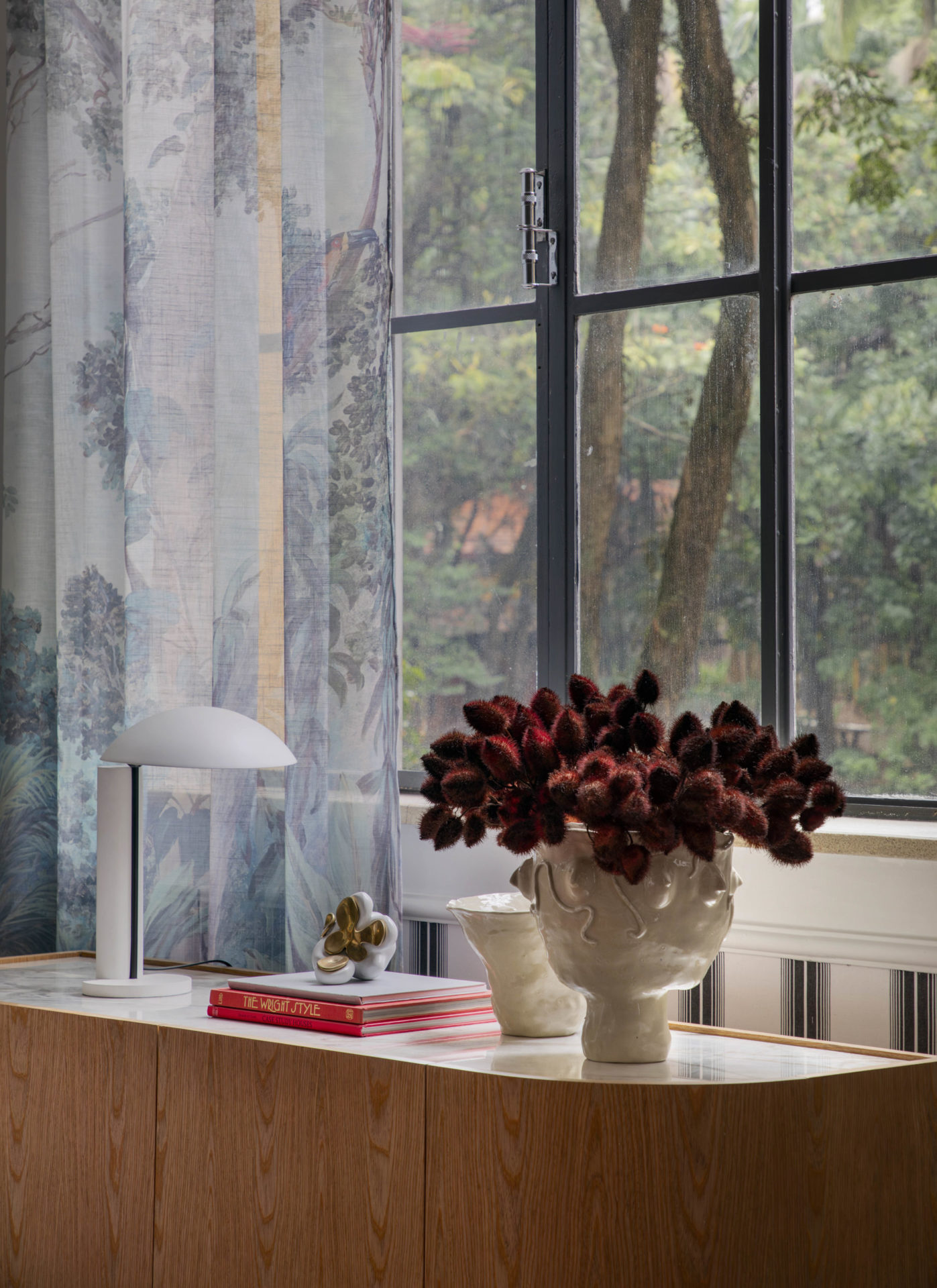 mesa com objetos e flores, janela e cortina 