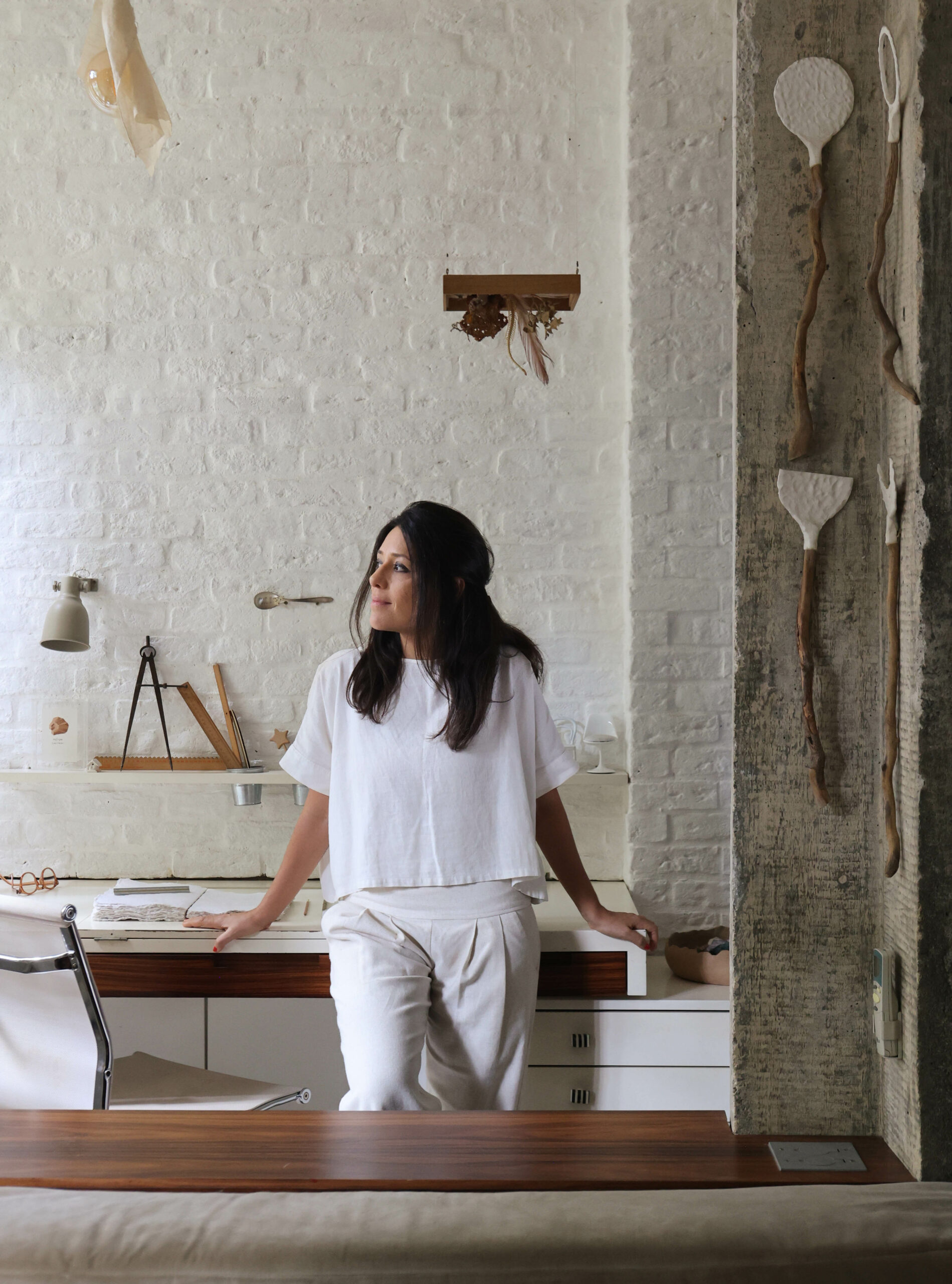 na foto mulher branca com roupa branca encostada na mesa do escritório também todo branco
