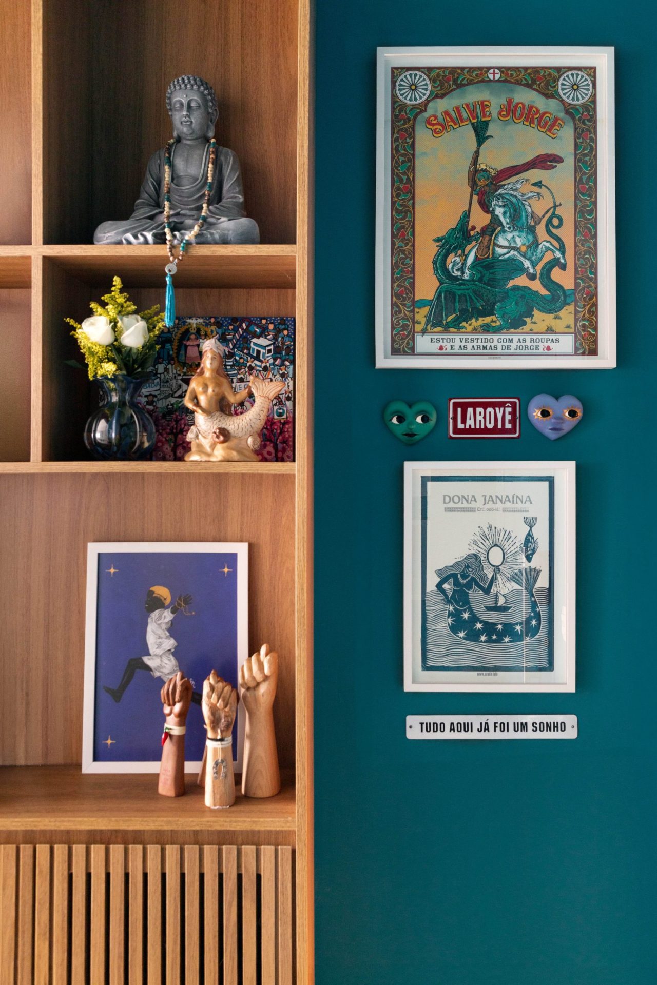 na foto uma parede azul e uma estante com obras de arte