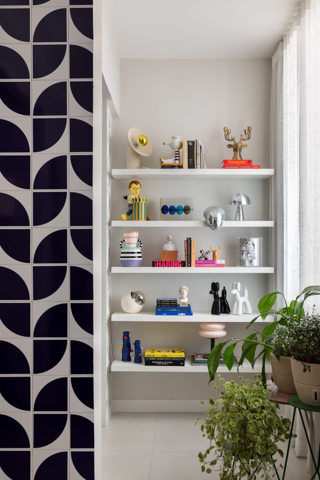 na foto uma sala com azulejos na sala e estante com objetos decorativos