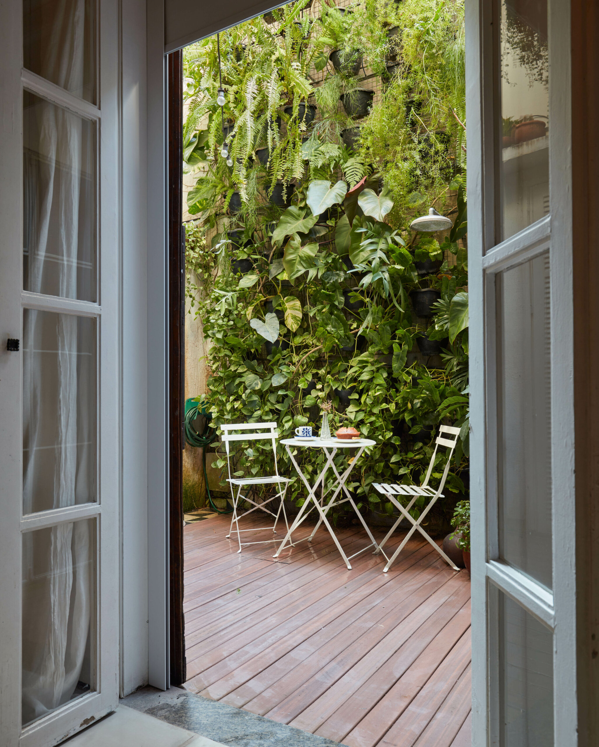 na foto um jardim vertical de apartamento com uma mesa com duas cadeiras