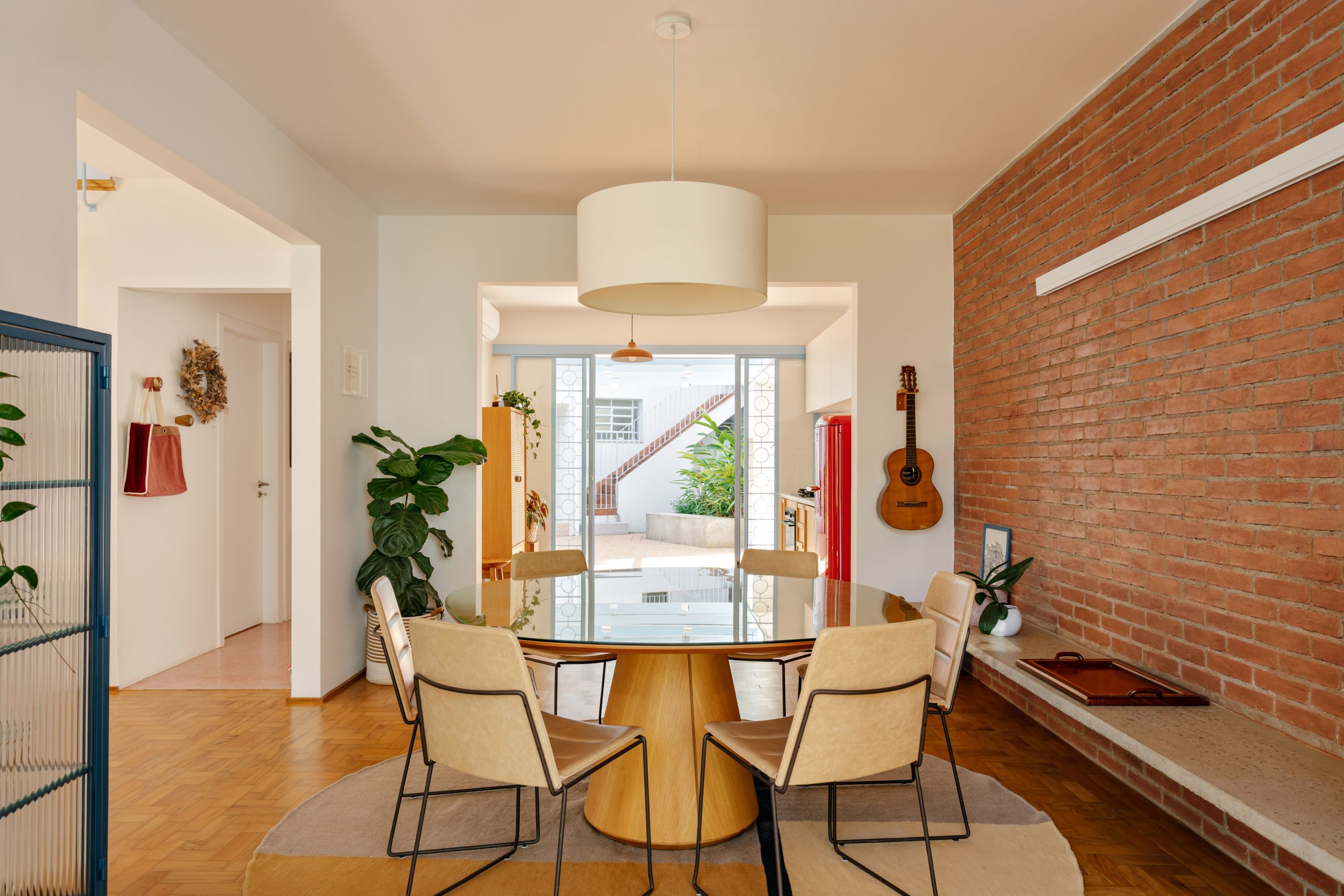 na foto sala de jantar com mesa redonda e cozinha com porta para área externa de casa de vila