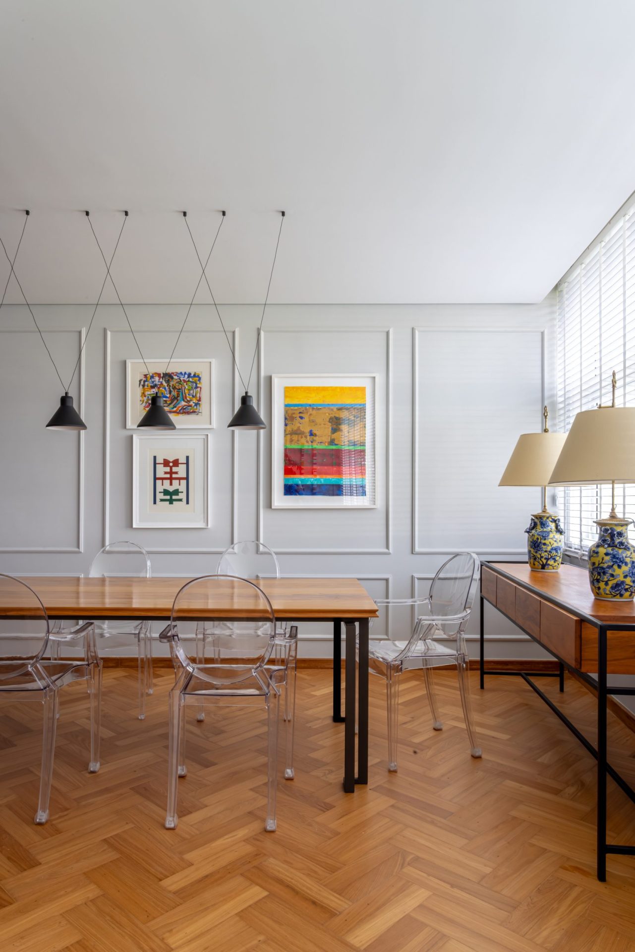 na foto sala de jantar com móveis contemporâneos e mesa de madeira e cadeiras de acrílico