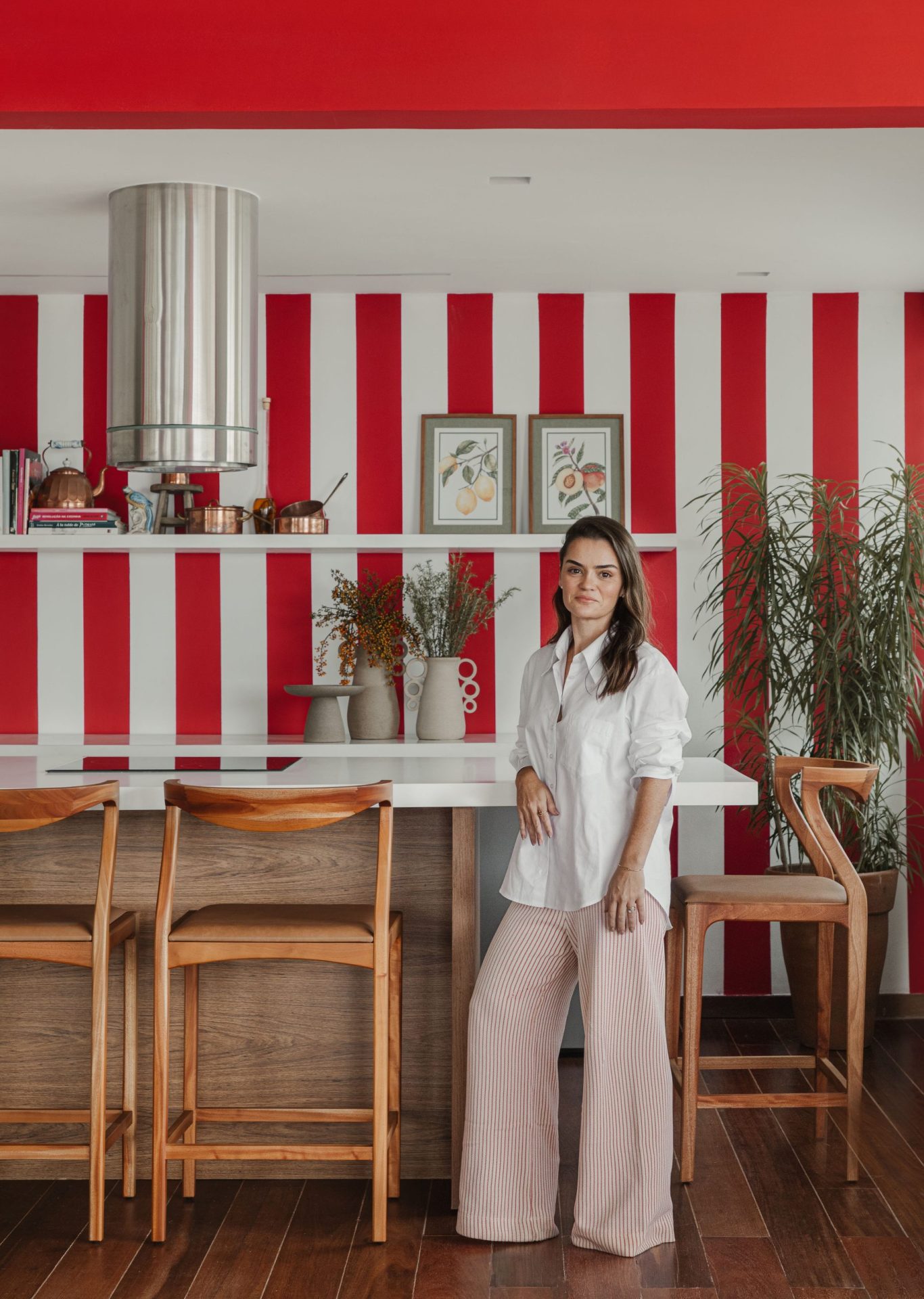 na foto mulher branca em pé, com roupra branca, cabelo comprido na área gourmet de apartamento