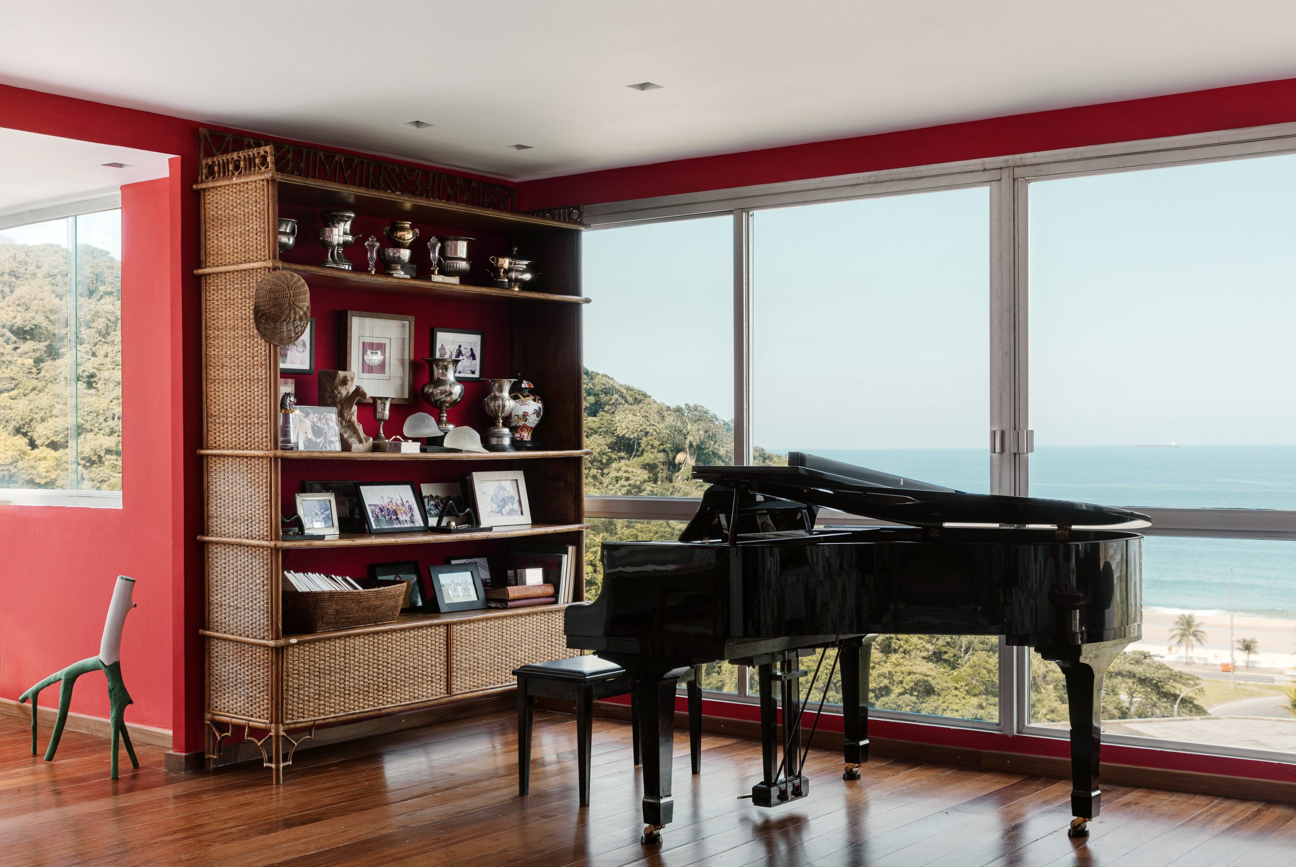 sala com piano e estante de madeira. grande janela com vista
