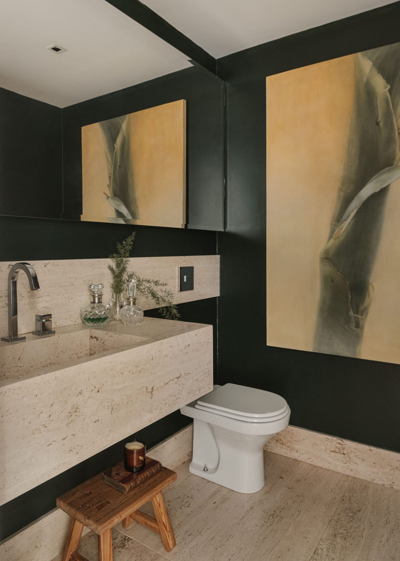 na foto lavabo com uma parede preta, grande espelho, bancada e vaso sanitário