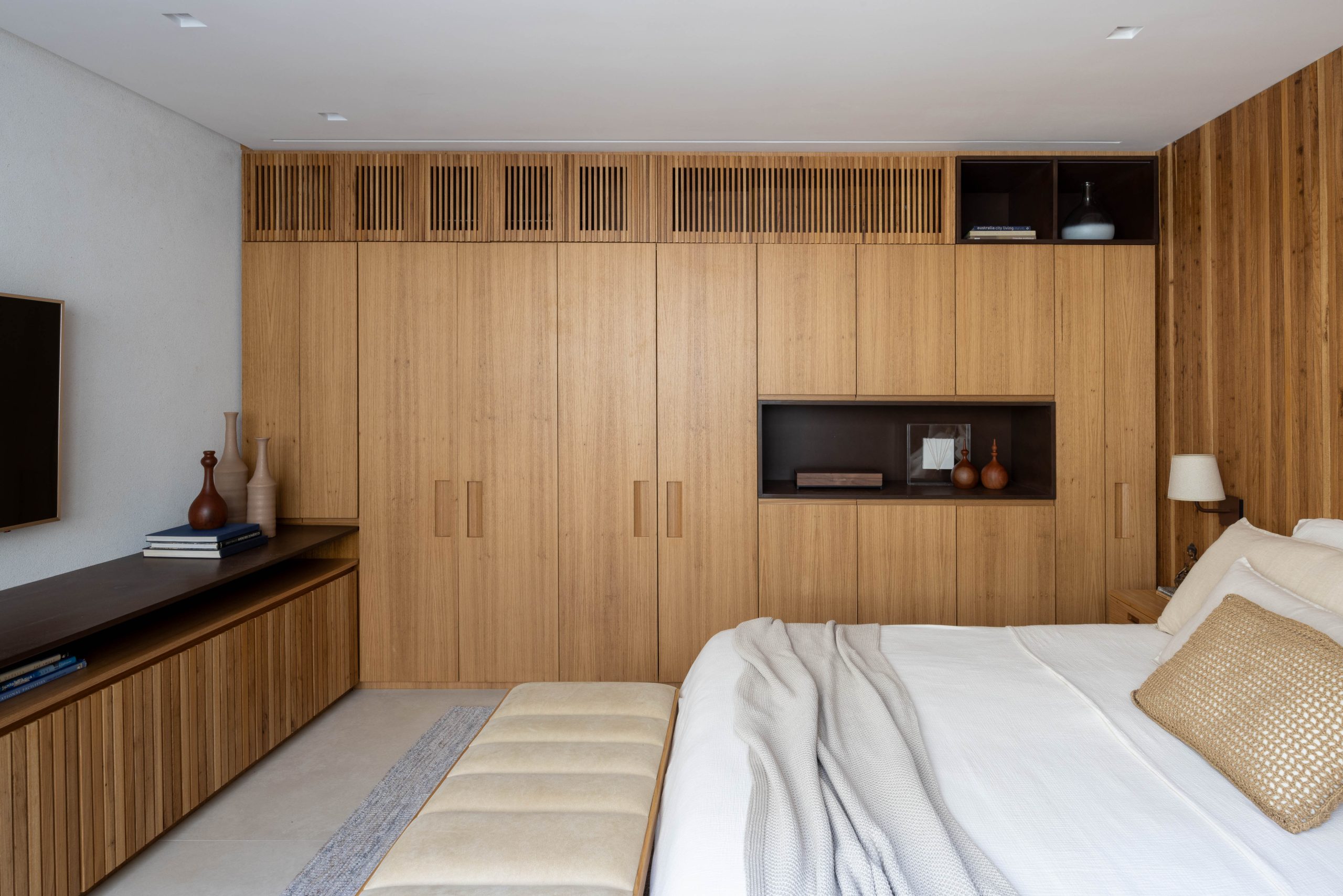 na foto suíte principal com cama de casal, armário em madeira e tv