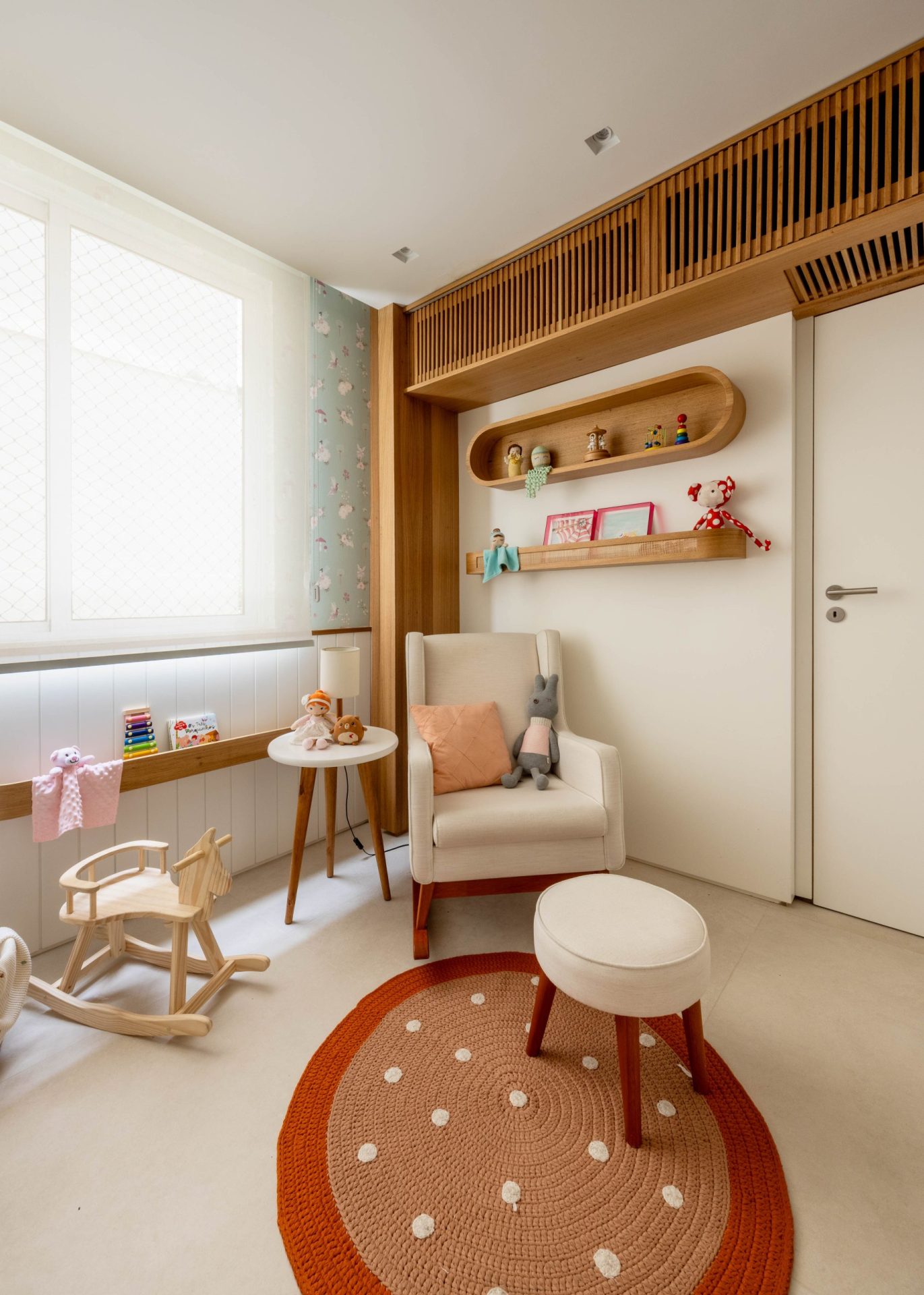 na foto quarto infantil com poltrona do bebê, janela, nichos com decoração infantil